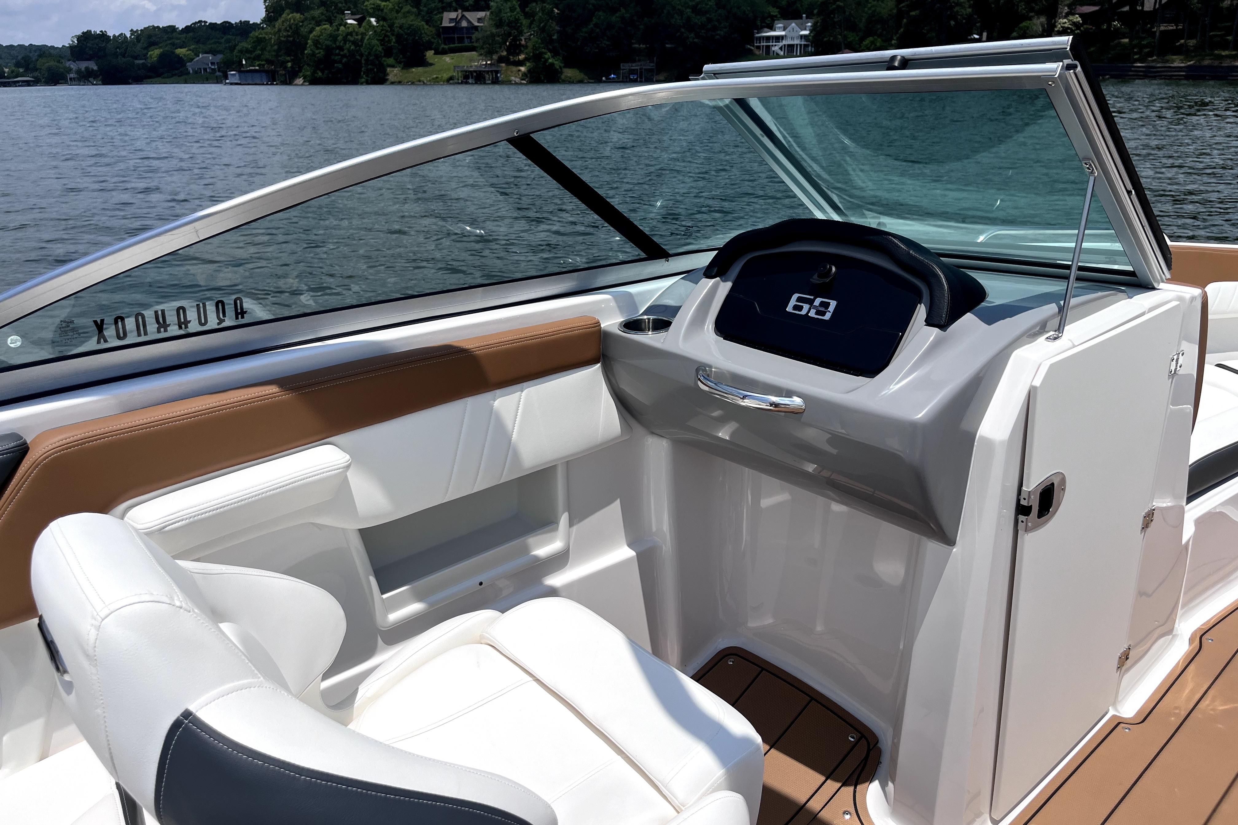 2025 Chaparral 230 SSi boat interior with sleek dashboard and comfortable seating on a lake.