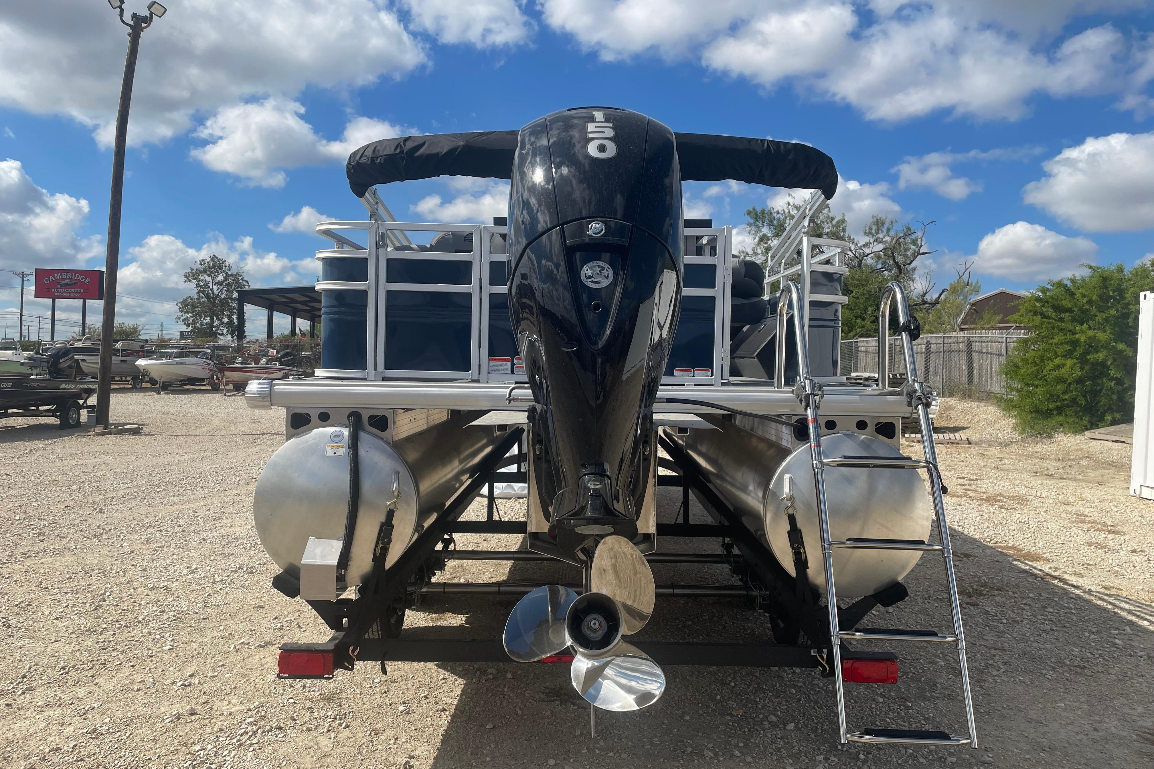 2026 Sun Tracker SportFish 22 DLX pontoon boat with powerful outboard motor, parked outdoors.