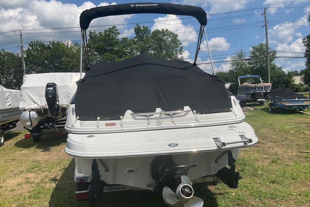 2015 Crownline 236 SC boat with black cover, parked on grass under a cloudy sky.