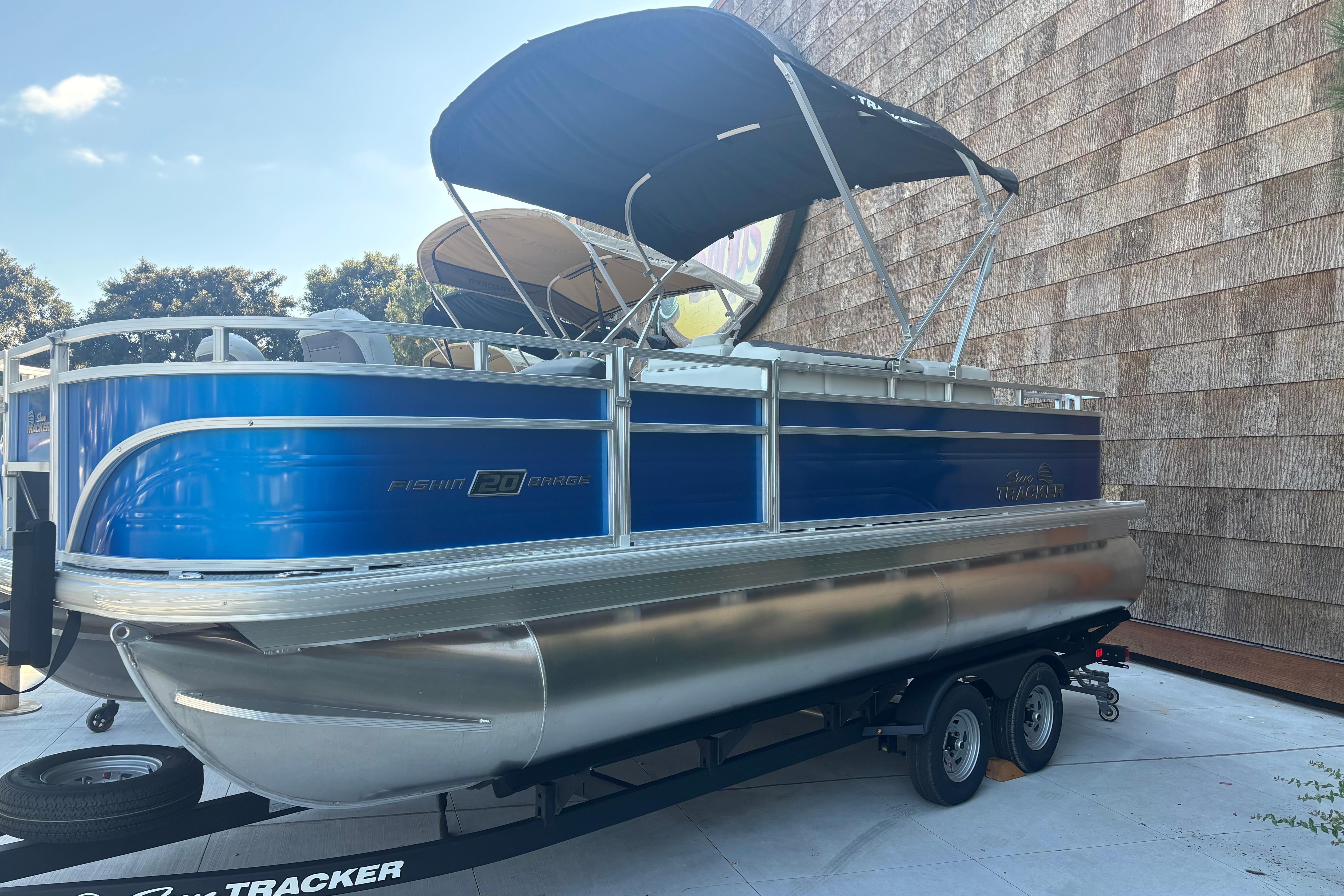 2026 Sun Tracker Fishin' Barge 20 DLX pontoon boat with canopy on trailer.