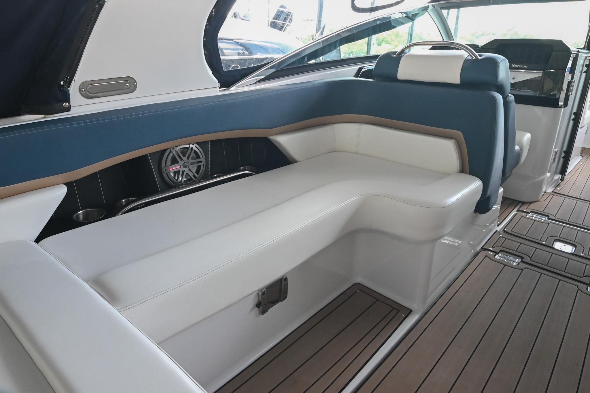 Interior of 2014 Four Winns H290 boat with white and blue seating, wooden flooring.