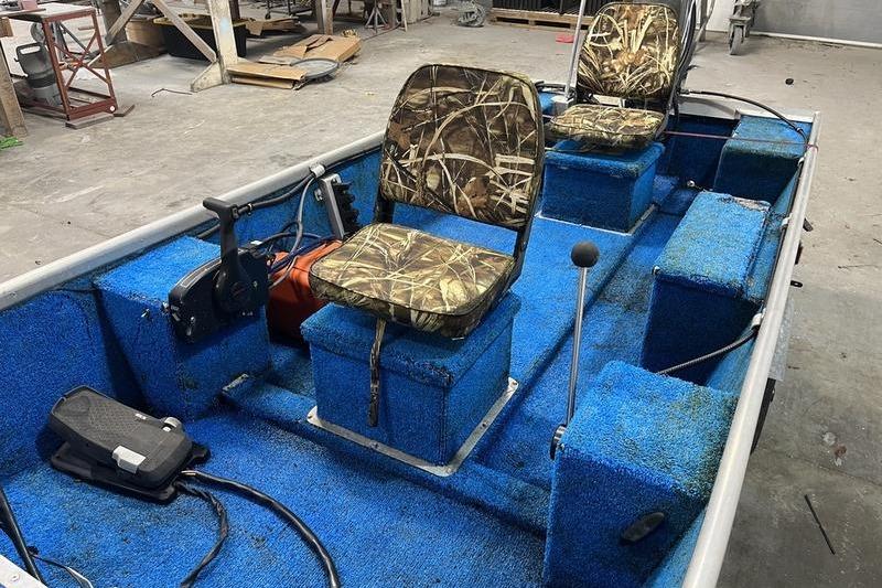 2006 SCANDY WHITE 1310 boat interior with blue carpet and camo seats in a workshop.