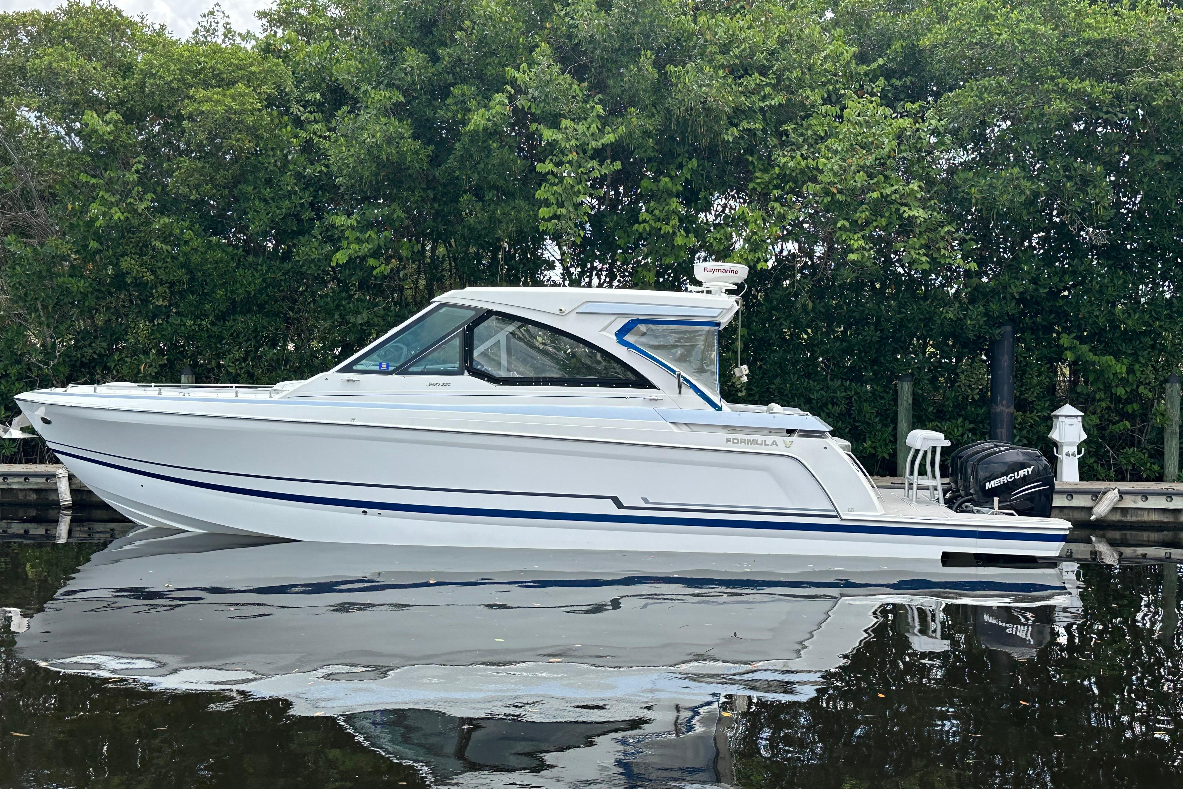2021 Formula 380 Super Sport Crossover OB boat docked by lush greenery.