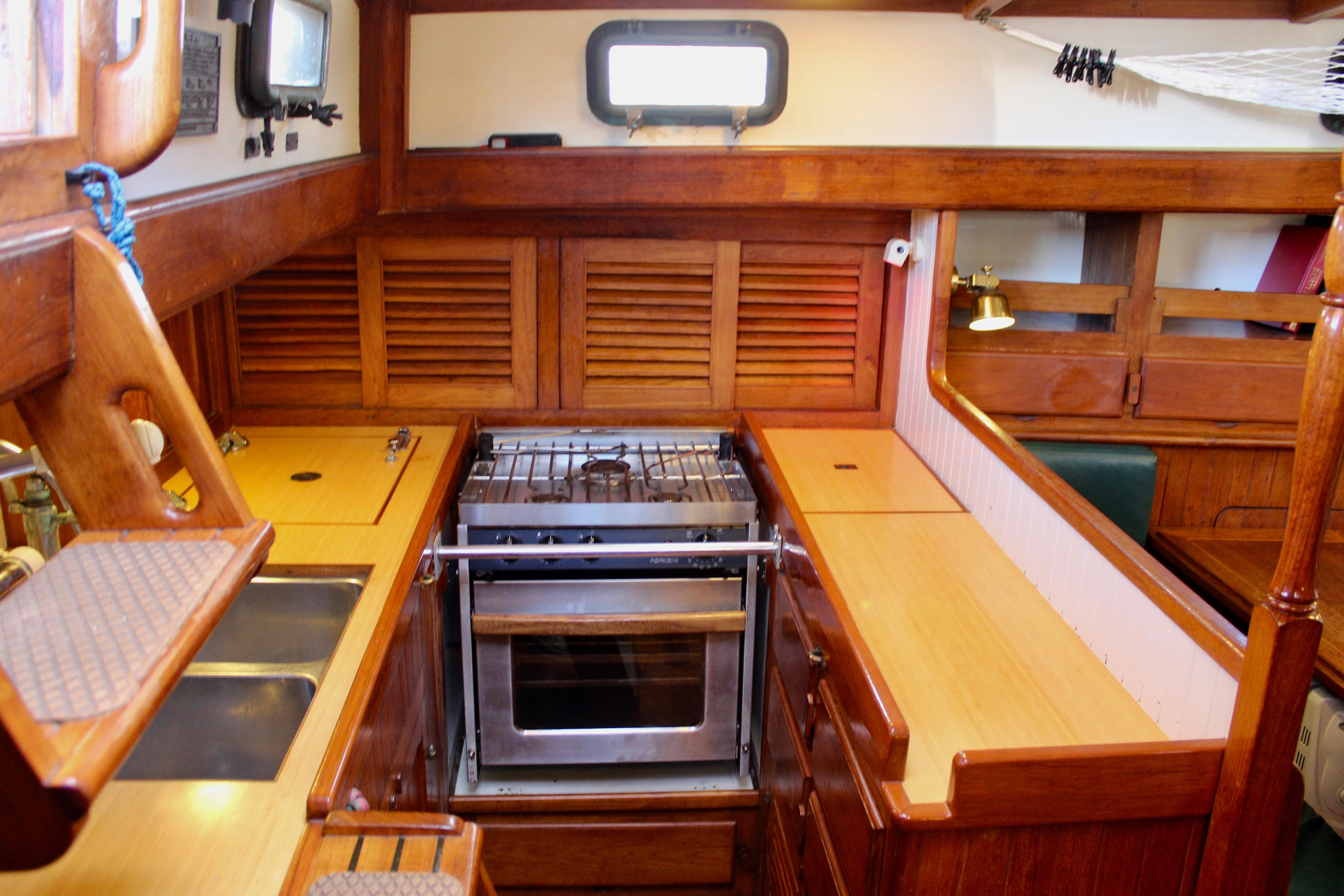 Interior of 1981 Kelly Peterson 46 yacht galley with wooden cabinetry and stove.