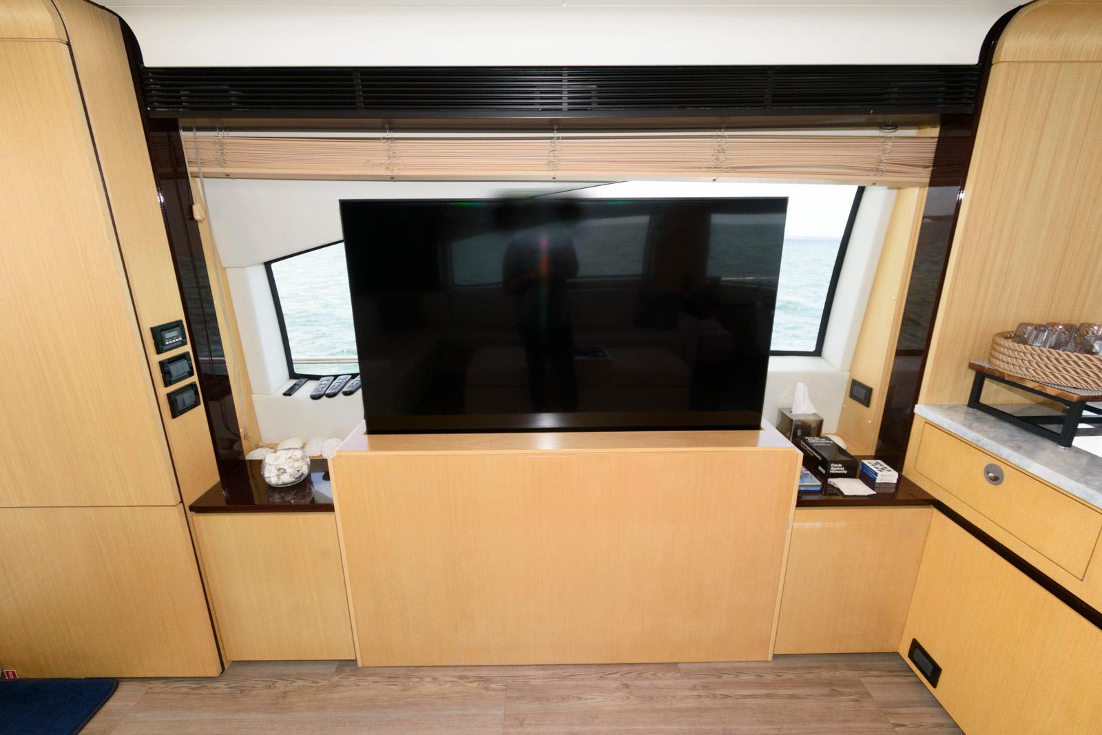 Luxurious interior of 2013 Azimut 84 Flybridge Yacht with large TV and wooden cabinetry.