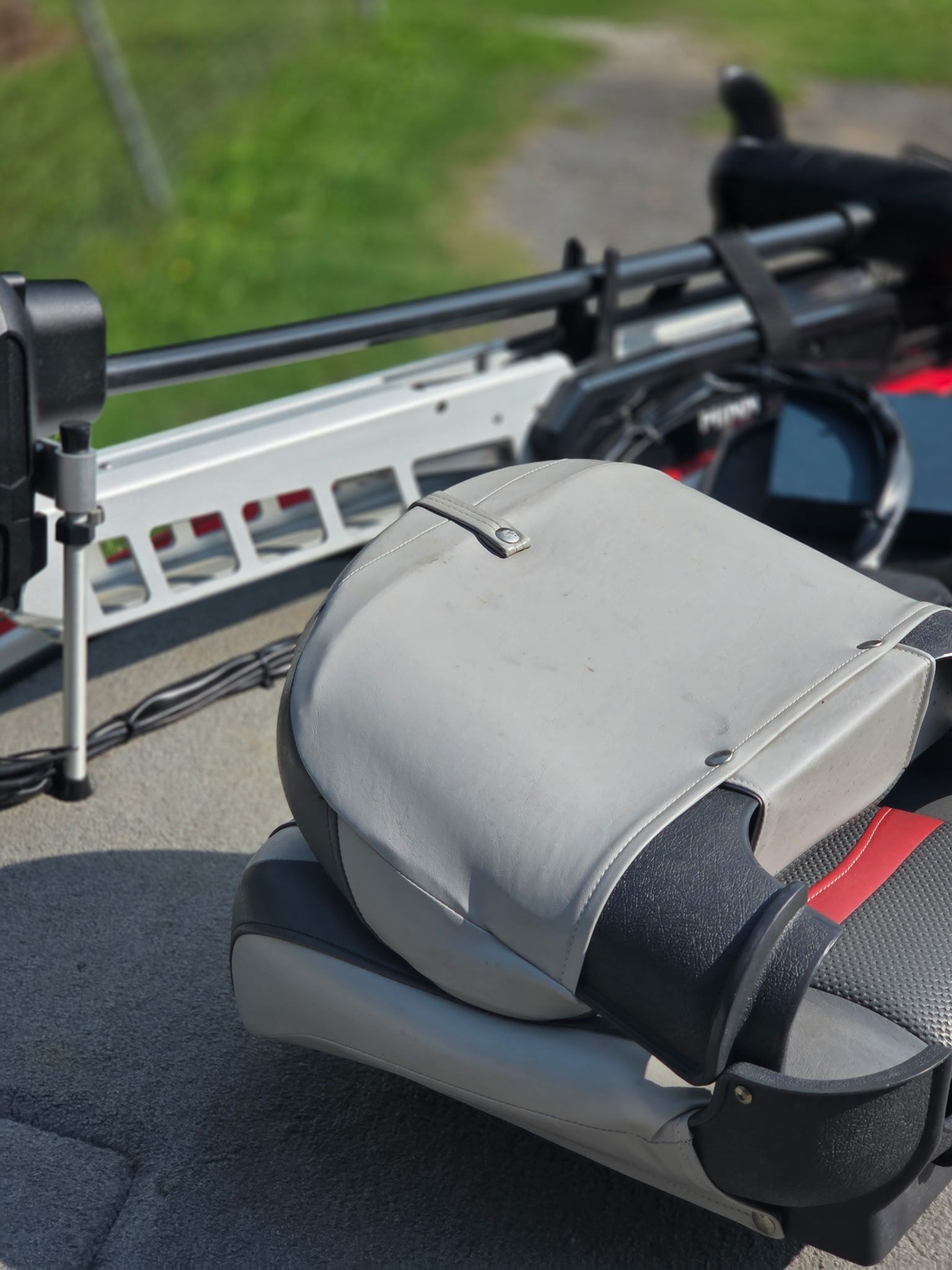 A gray seat on a boat with fishing rod holders.