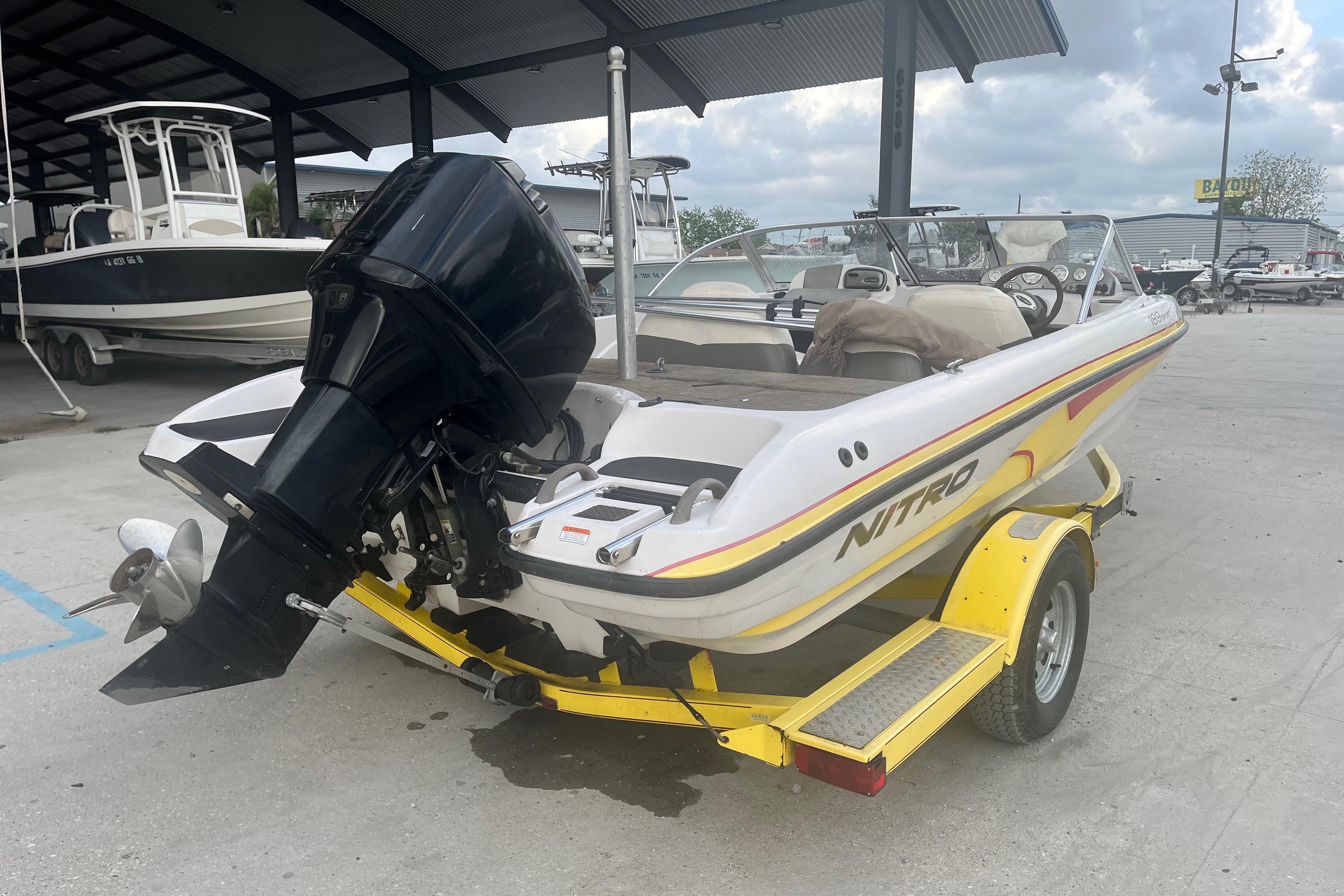 2006 Nitro 189 Sport boat on yellow trailer, parked in marina.