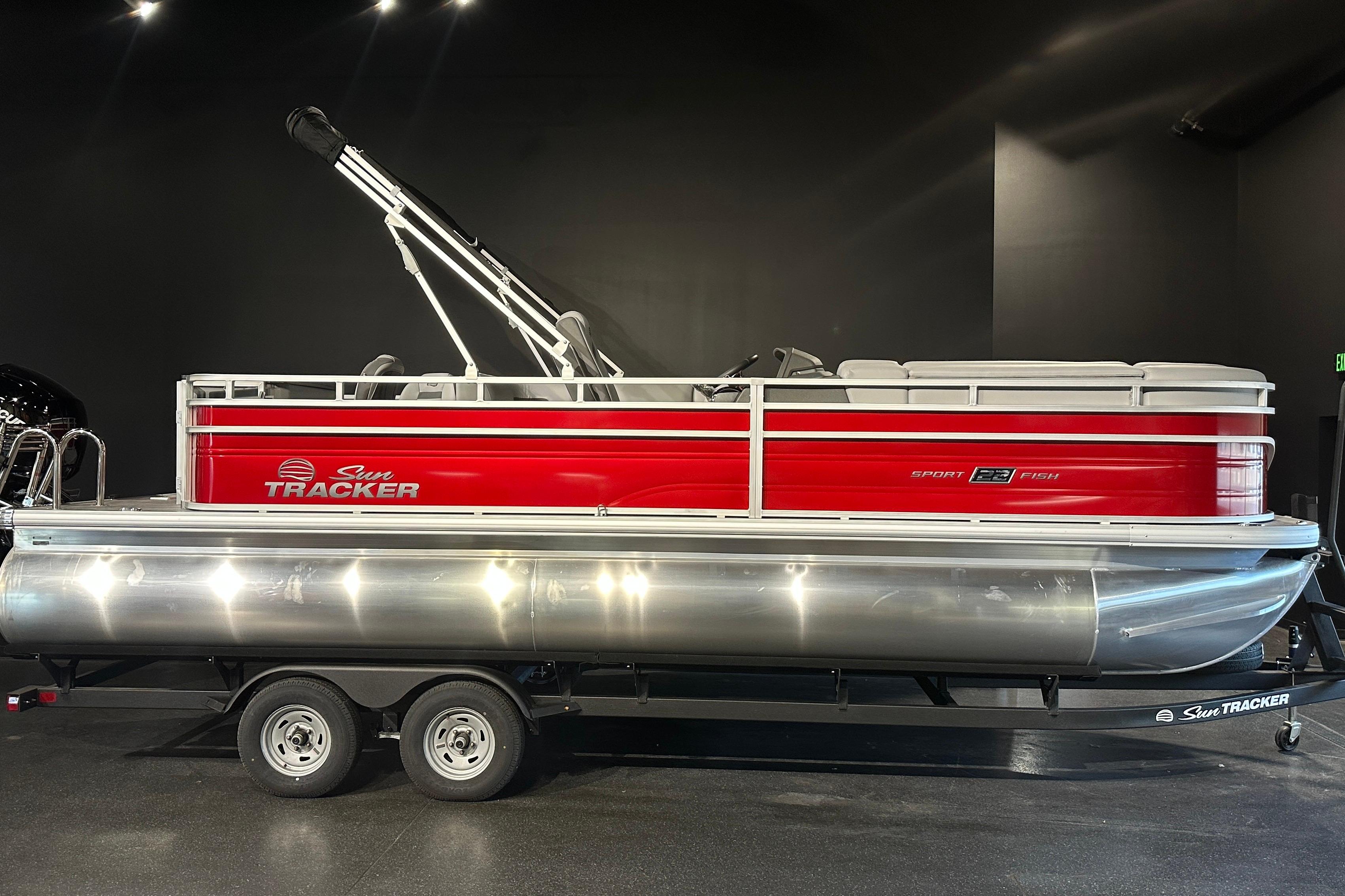 2026 Sun Tracker SportFish 22 DLX pontoon boat with red and silver design on trailer.