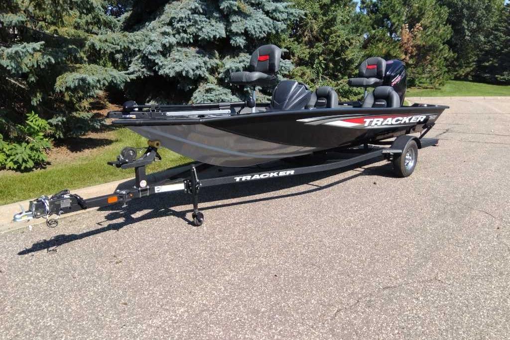 2026 Tracker Pro Team 190 boat on trailer, parked outdoors, surrounded by trees.