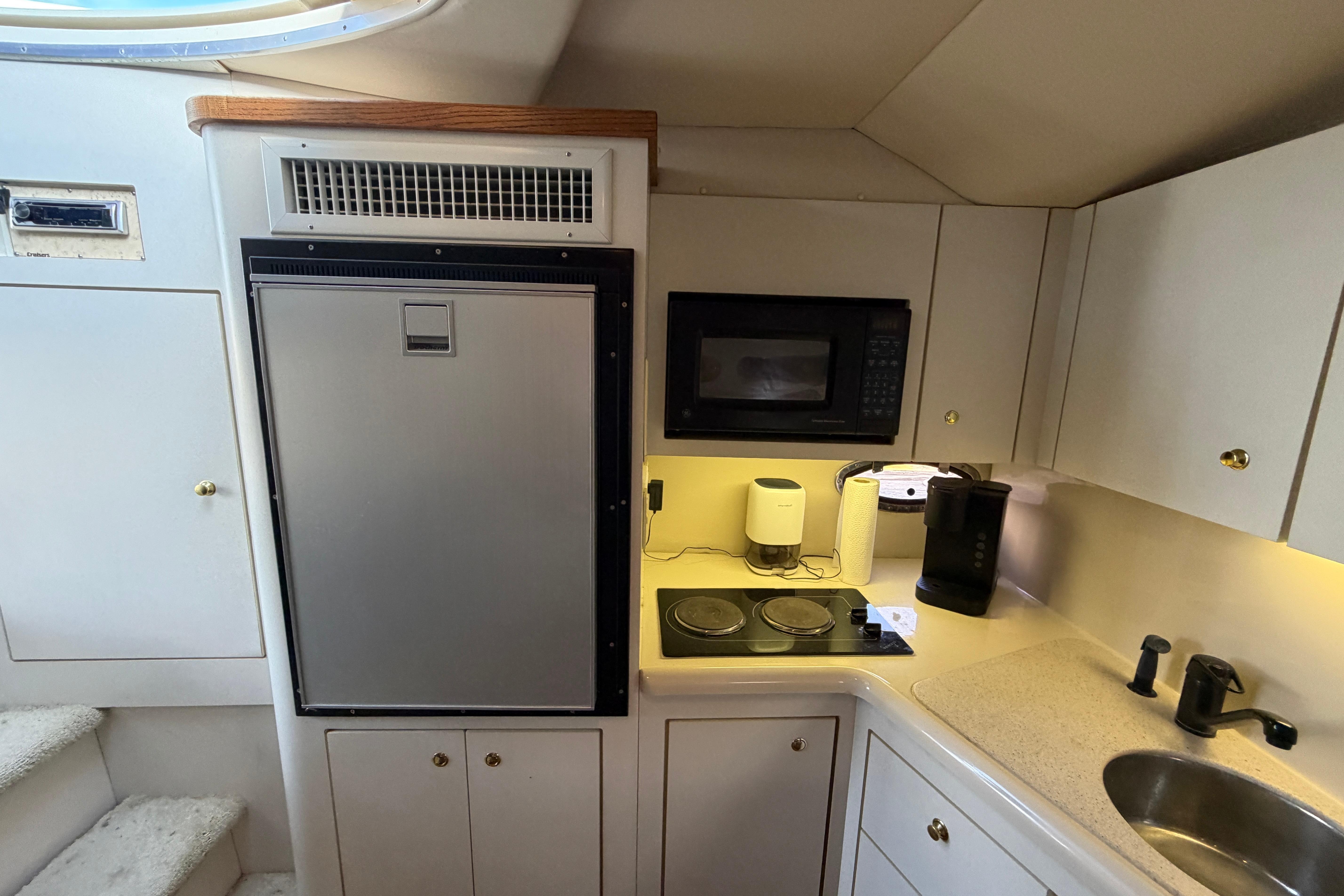 1997 Cruisers 3575 yacht kitchen with fridge, microwave, stove, and sink.