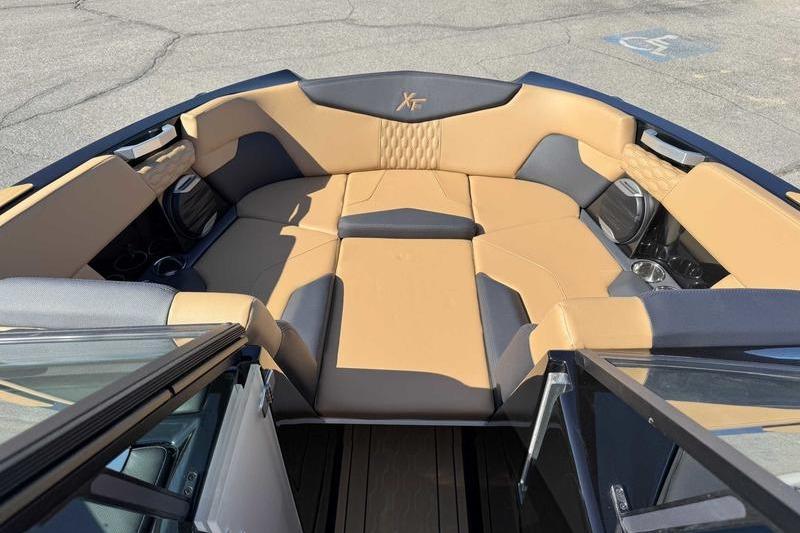2026 MasterCraft XT22 boat interior with tan and gray seating, featuring cup holders and speakers.