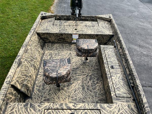 2024 Lowe Roughneck 1660 camo fishing boat interior with seats and storage compartments.