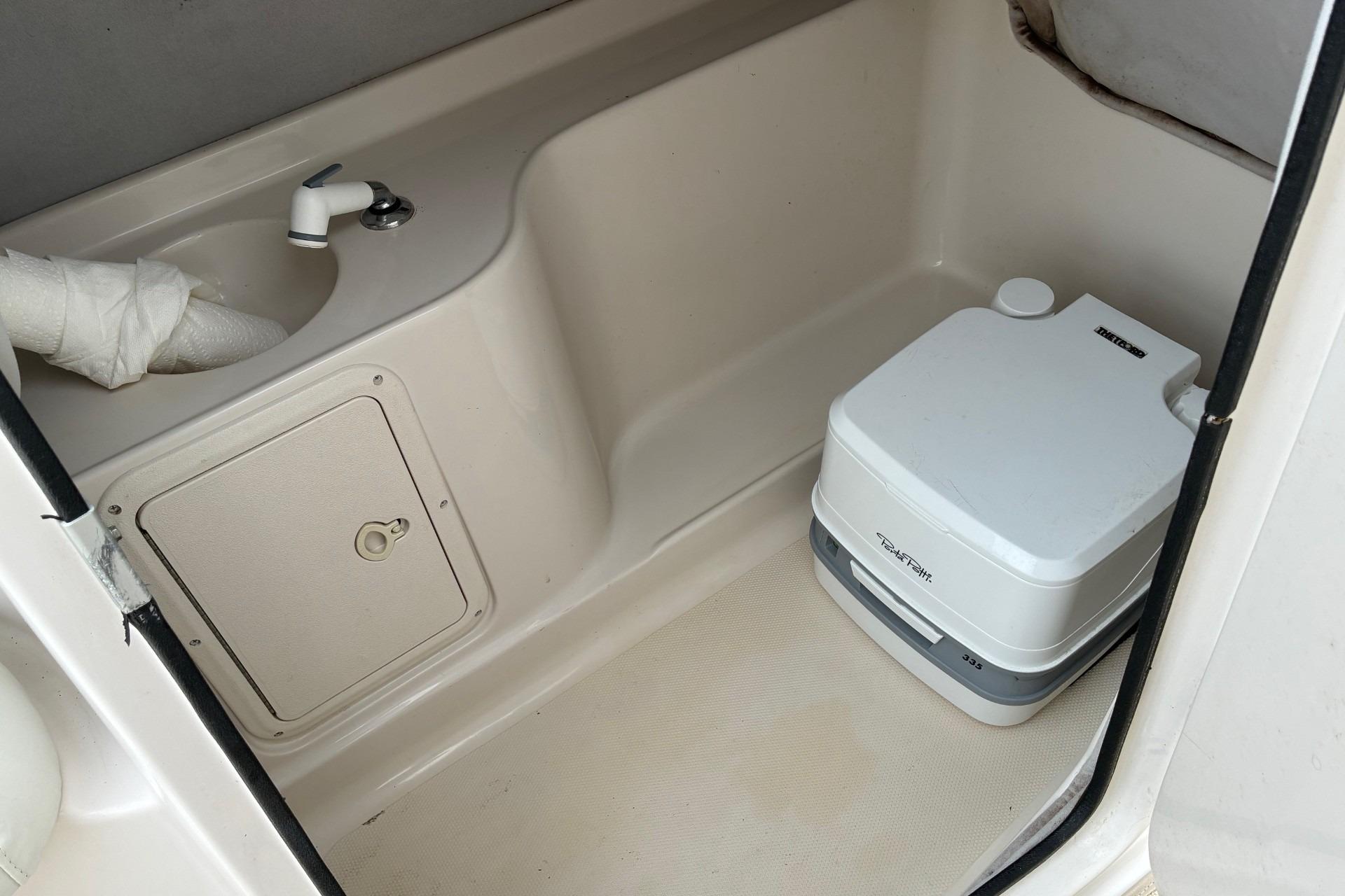 Compact bathroom in 2003 Hurricane 234 SD boat with sink and portable toilet.
