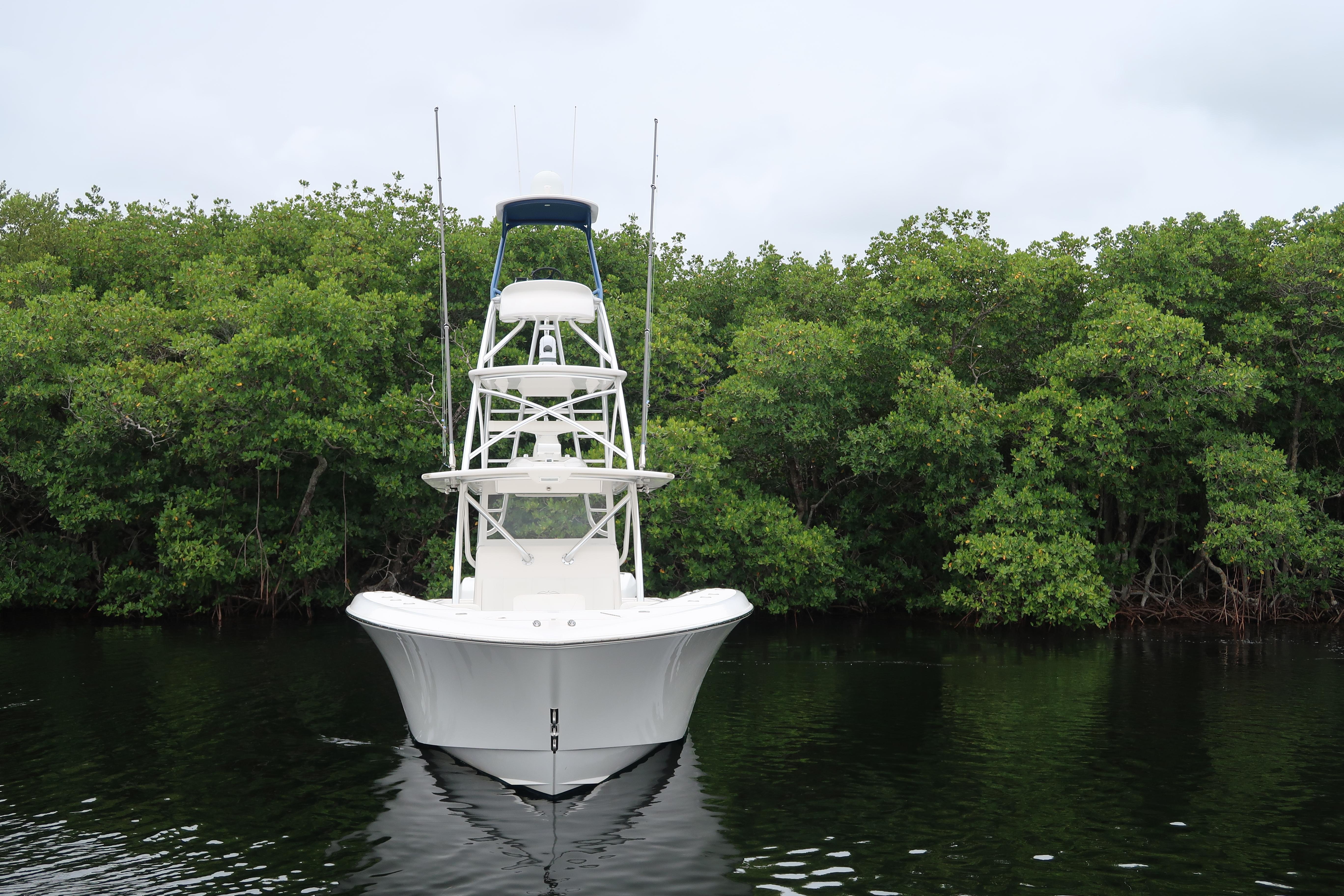 2016 Invincible 42 Open Fisherman boat on calm water with lush green background.