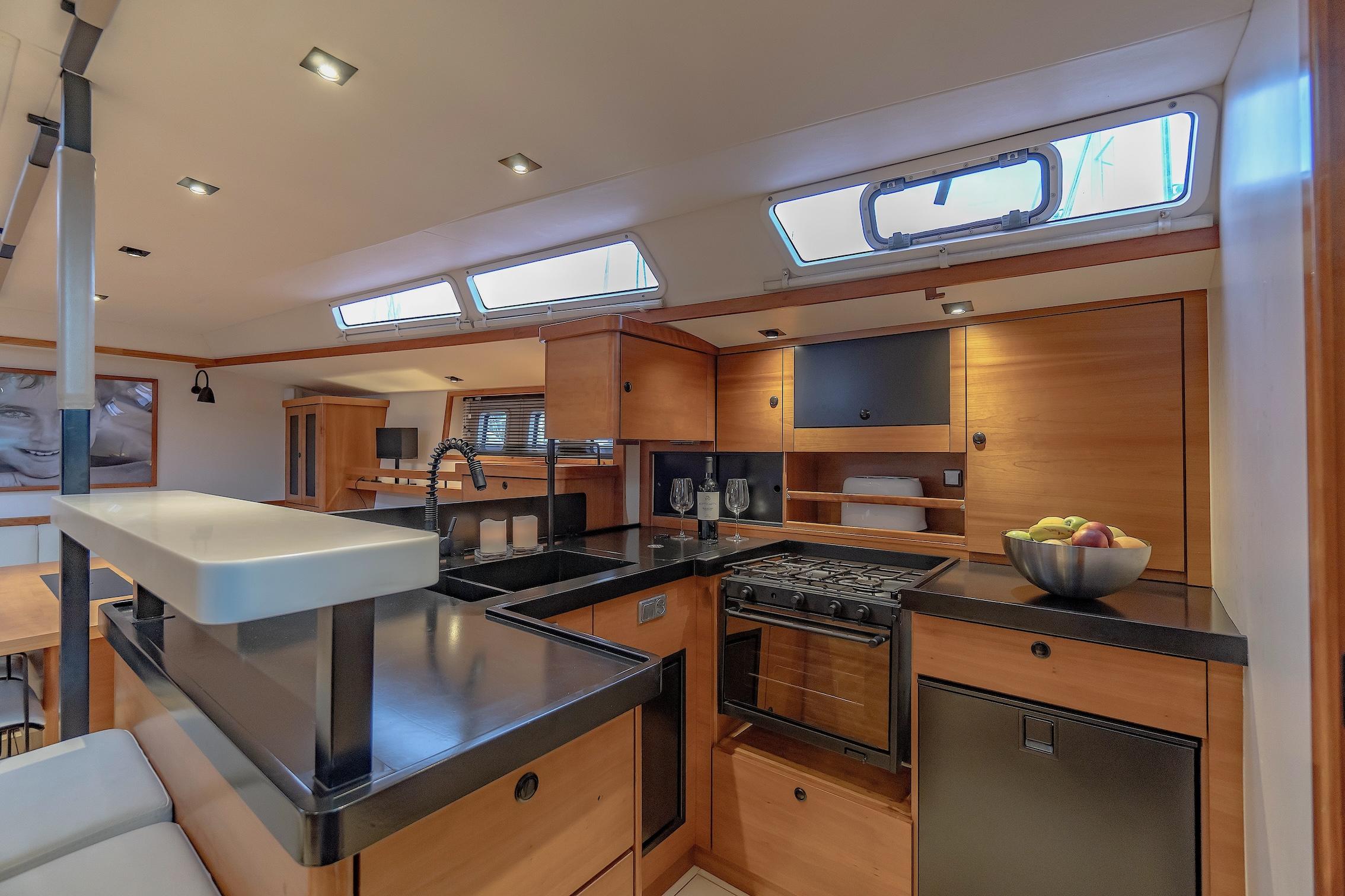 Luxurious 2009 Hanse 630e yacht interior kitchen with modern amenities and sleek wooden cabinetry.