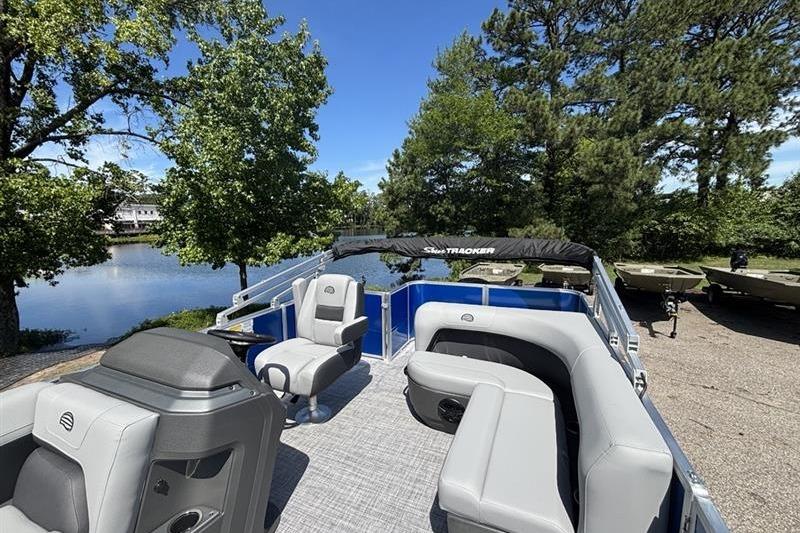 2026 Sun Tracker Party Barge 18 DLX pontoon boat with spacious seating, docked by a scenic lake.