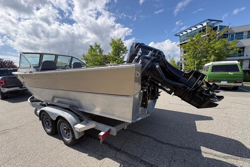 2009 Alumaweld Intruder Outboard 22 boat on trailer, parked outdoors under a cloudy sky.
