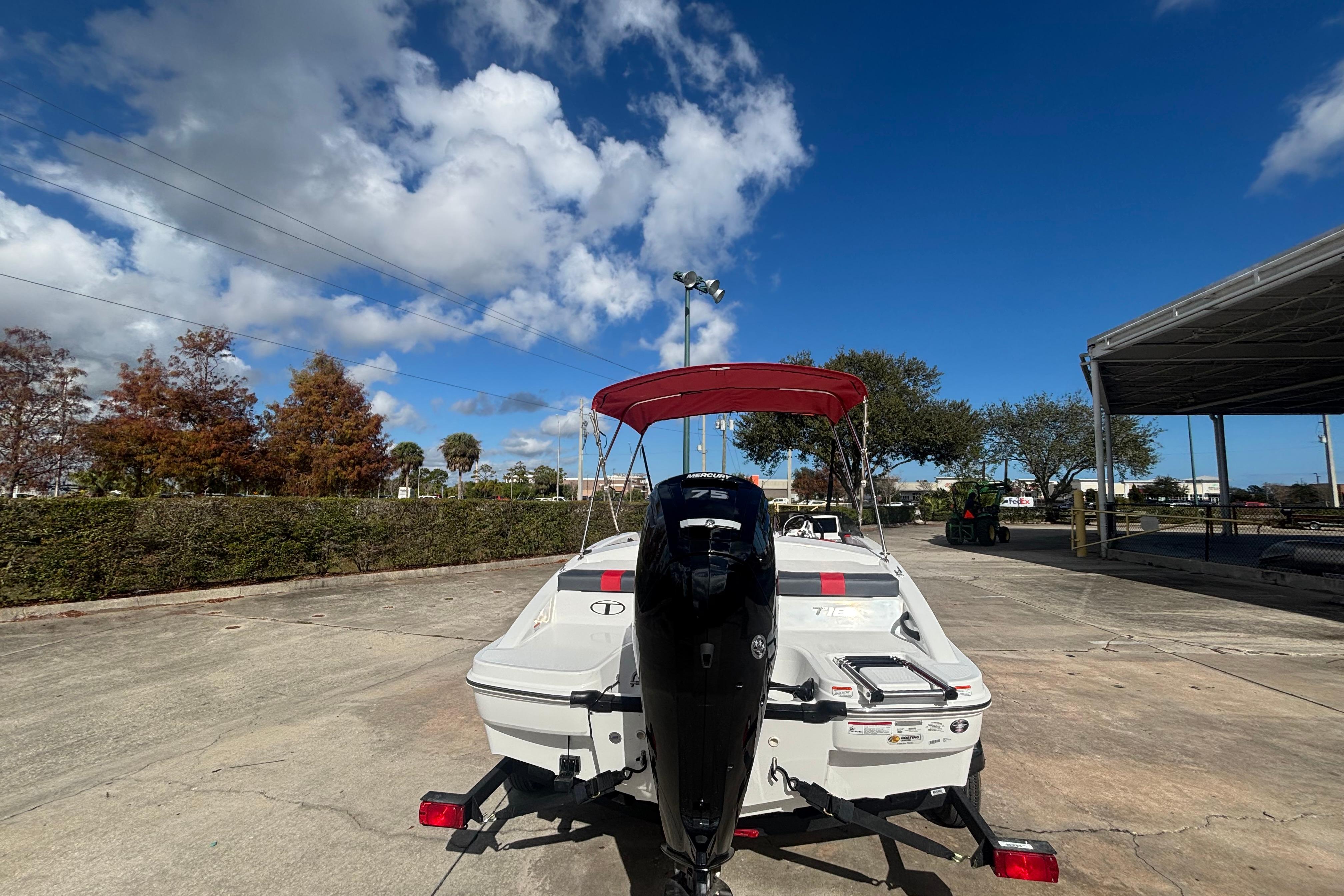 2026 Tahoe T16 boat with outboard motor, parked outdoors under a clear blue sky.