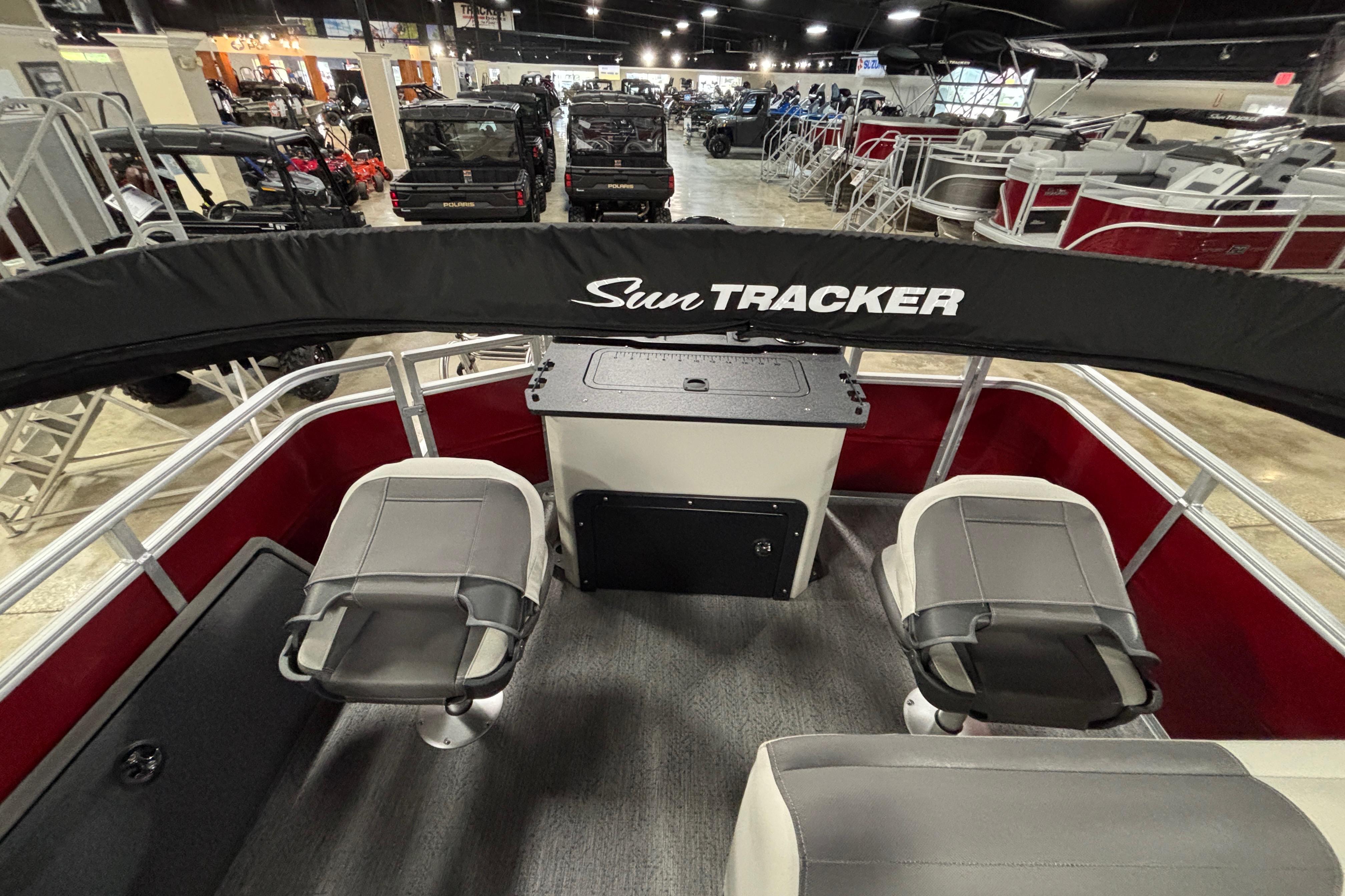 2026 Sun Tracker Fishin' Barge 22 DLX interior with seating and console in showroom.