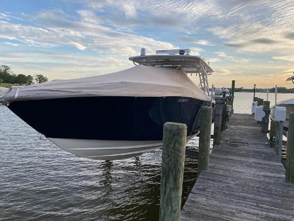 2019 Midnight Express 39 Cuddy boat docked, covered, under a cloudy sky.