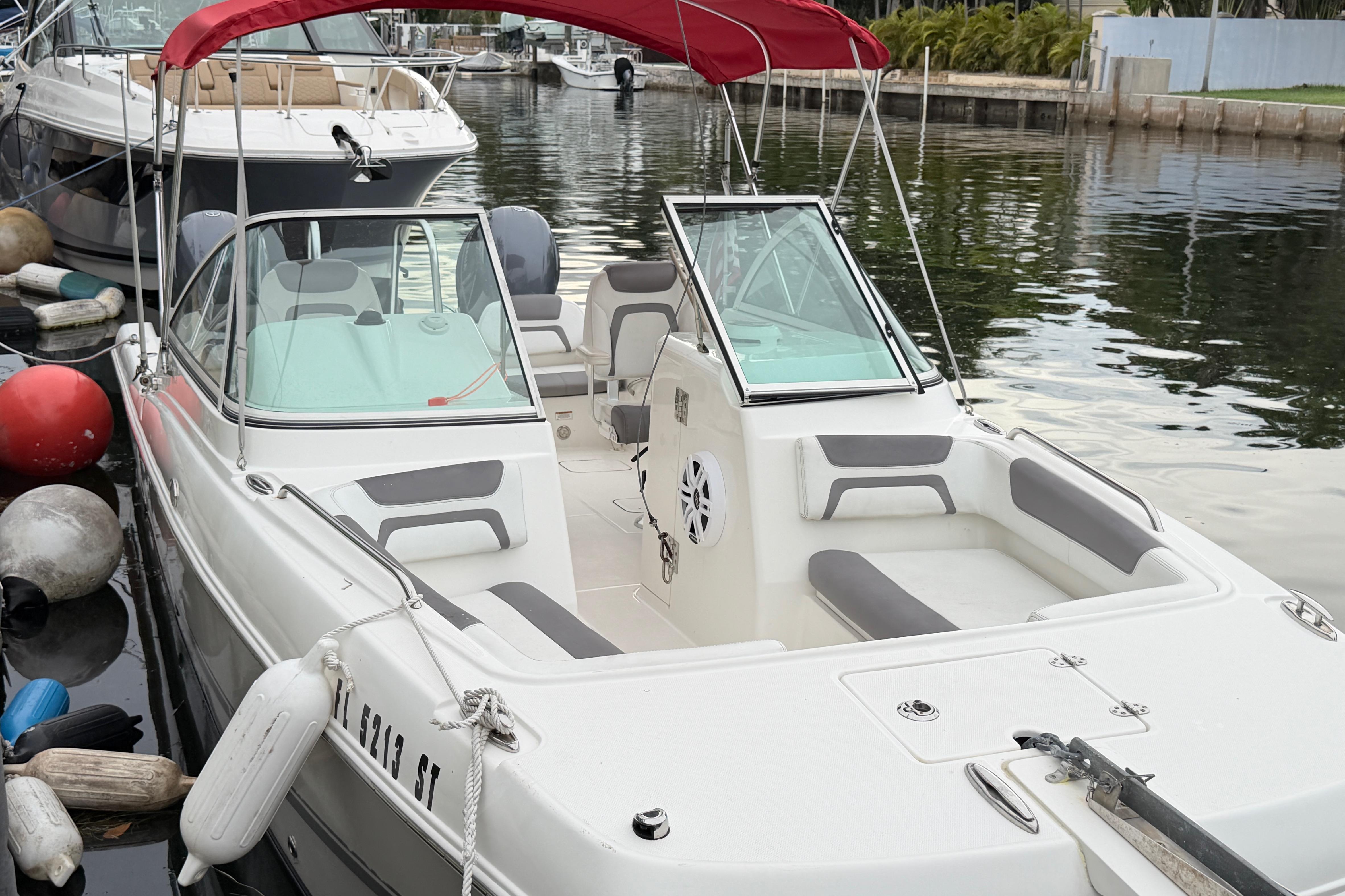 2019 World Cat 230 DC boat docked with red canopy and spacious seating.