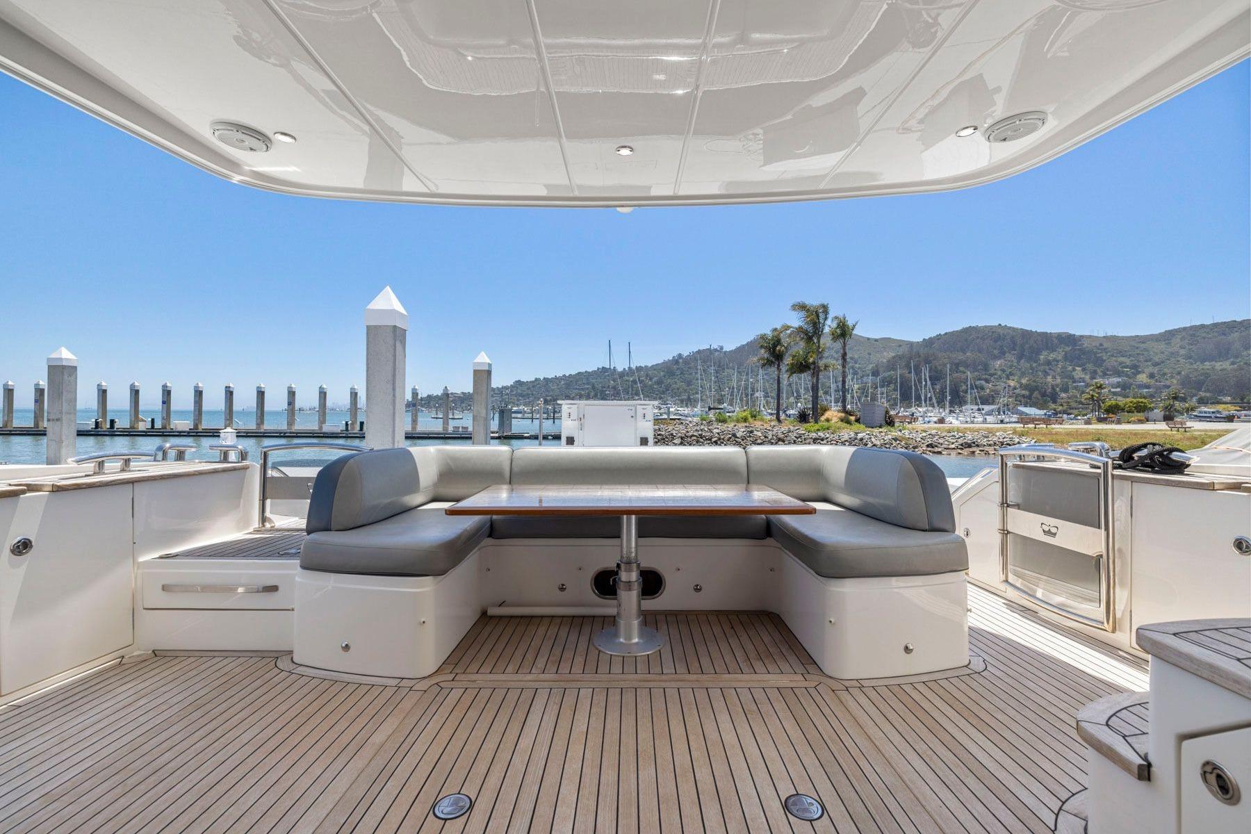 Luxurious 2015 Princess 60 Flybridge Motor Yacht deck with seating and scenic marina view.
