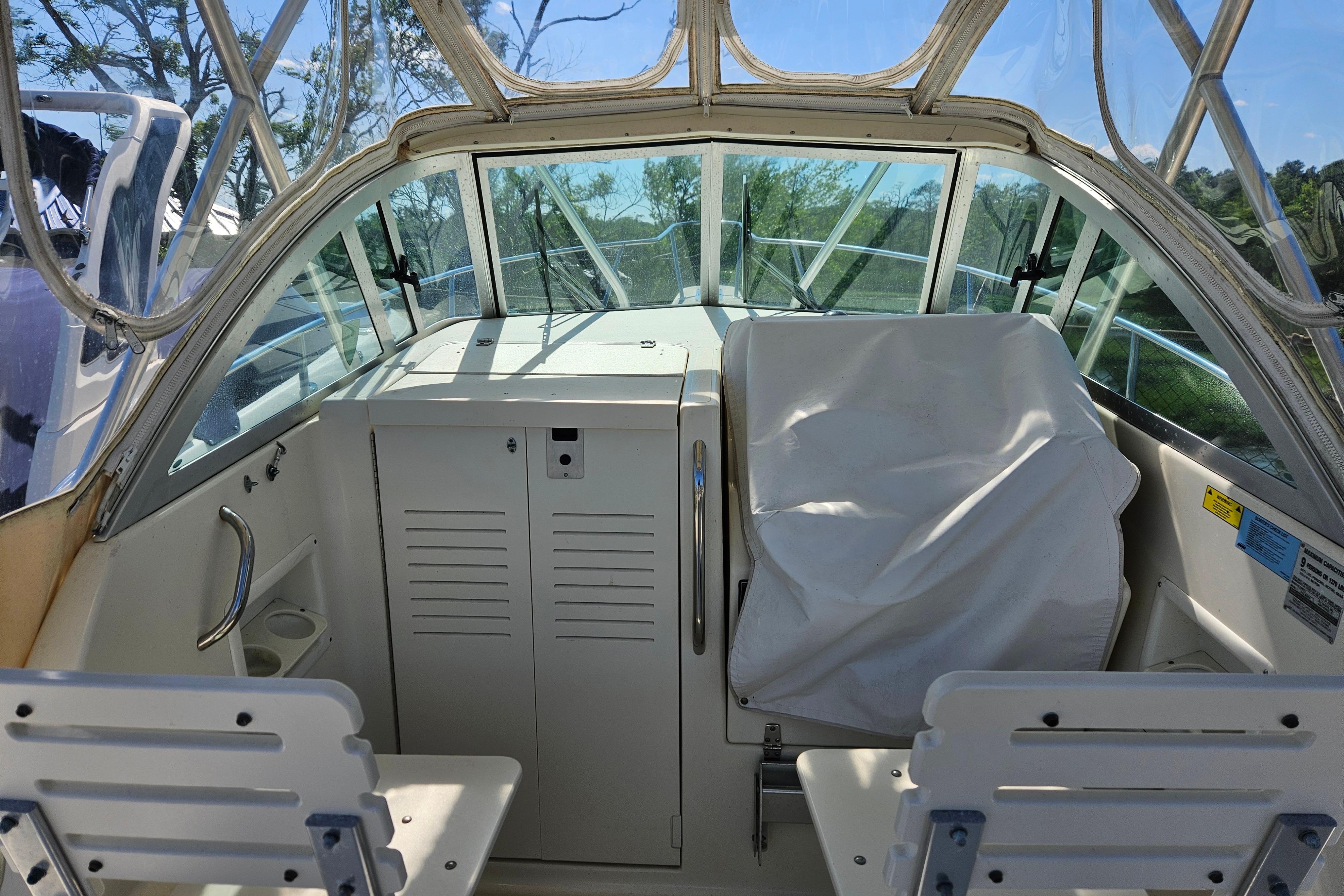 2004 Pursuit 2470 Walkaround boat cockpit with covered seating and clear canopy.