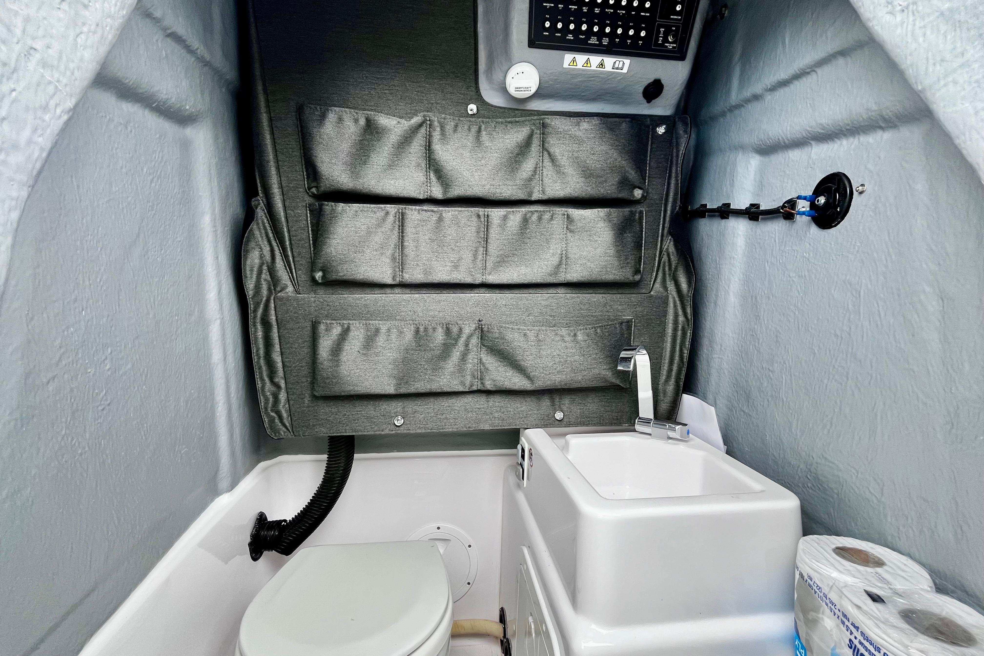Interior of 2023 Axopar 22 T-Top boat featuring compact bathroom with sink and storage.