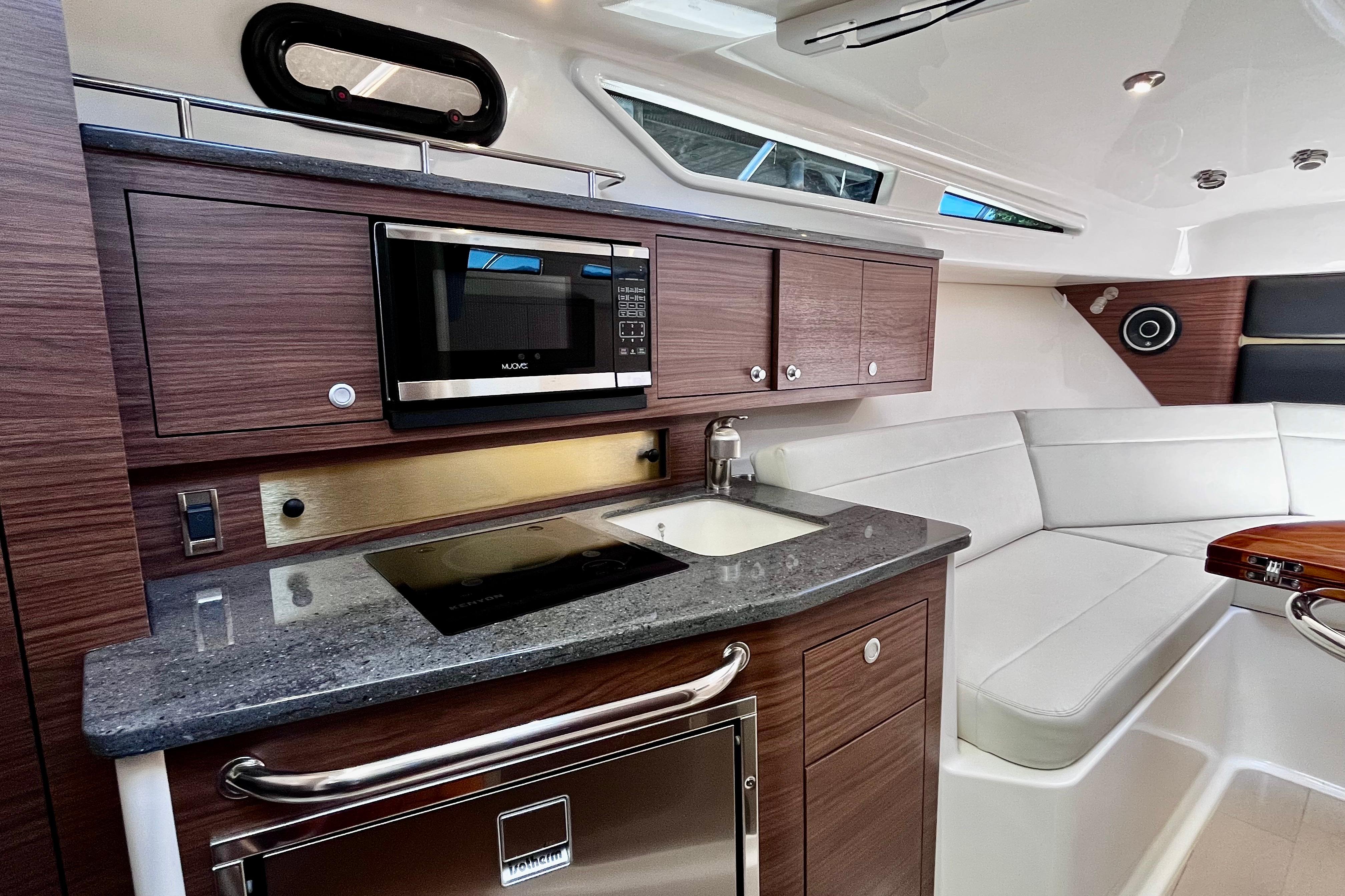 Luxurious interior of 2026 Boston Whaler 325 Conquest Pilothouse with modern kitchen amenities.