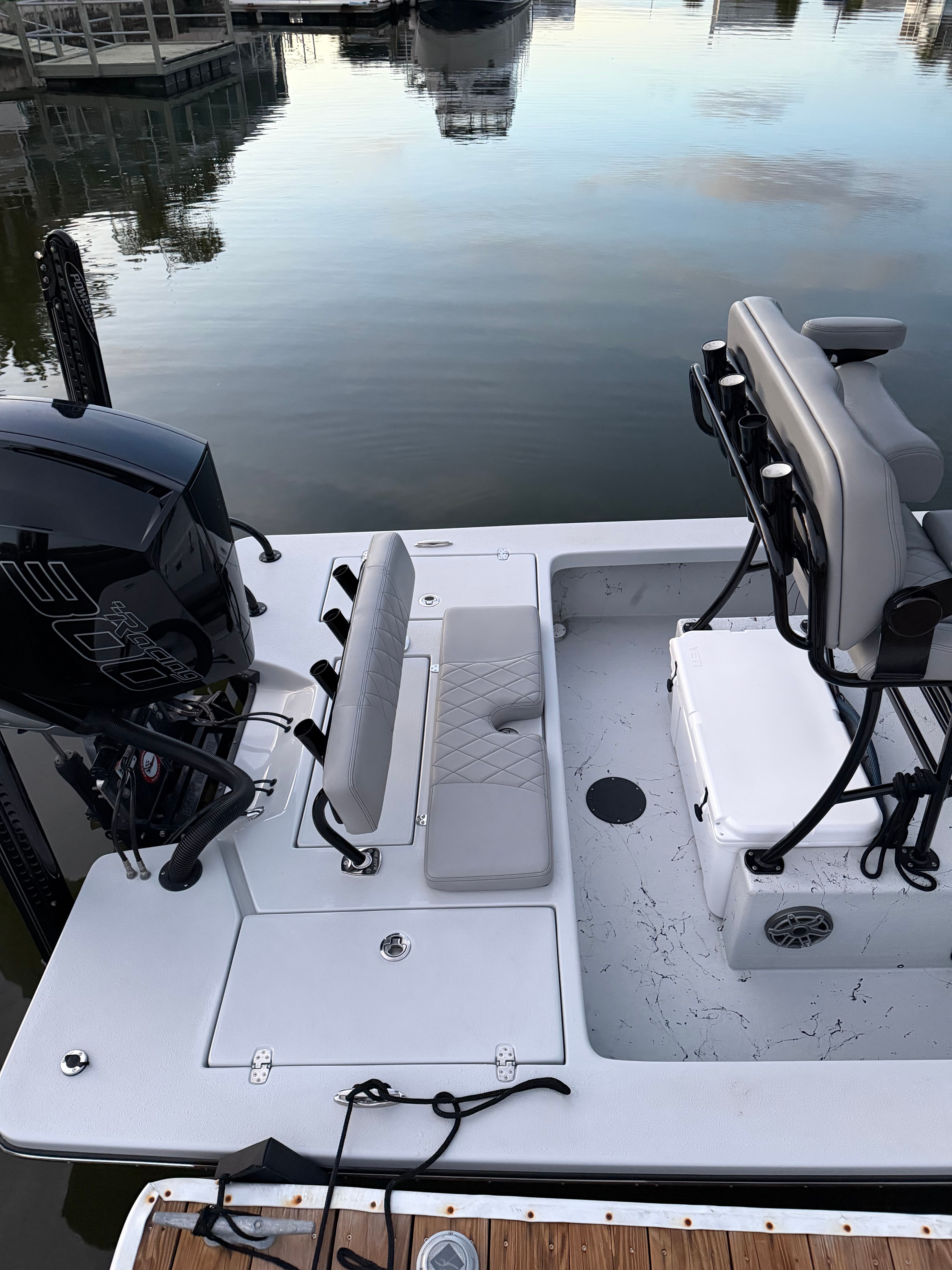 A 2022 Blazer Bay 2420 GTS with gray upholstery and an outboard motor, docked at a pier.