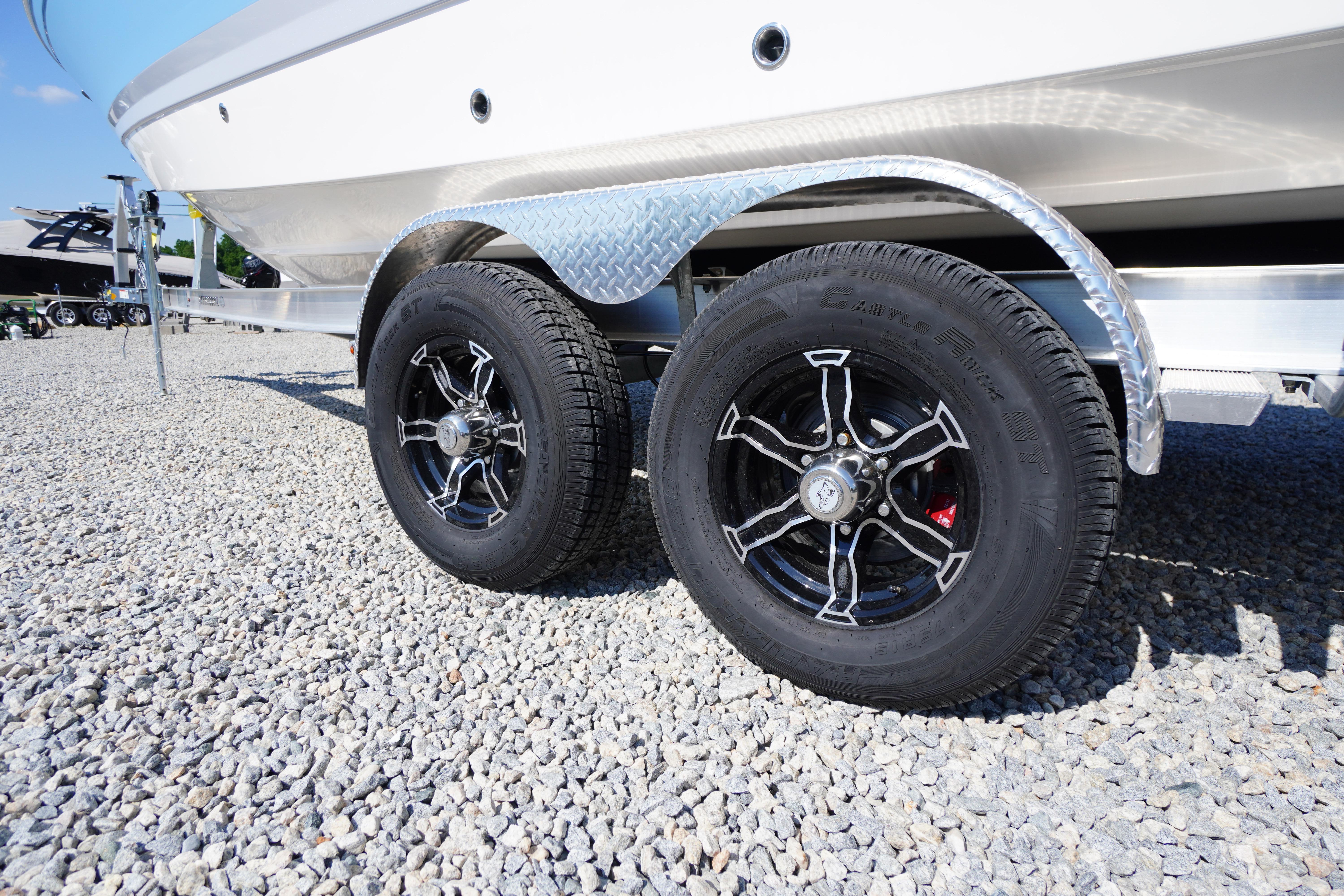 Trailer wheels of a 2026 Chaparral 270 OSX boat on gravel surface.