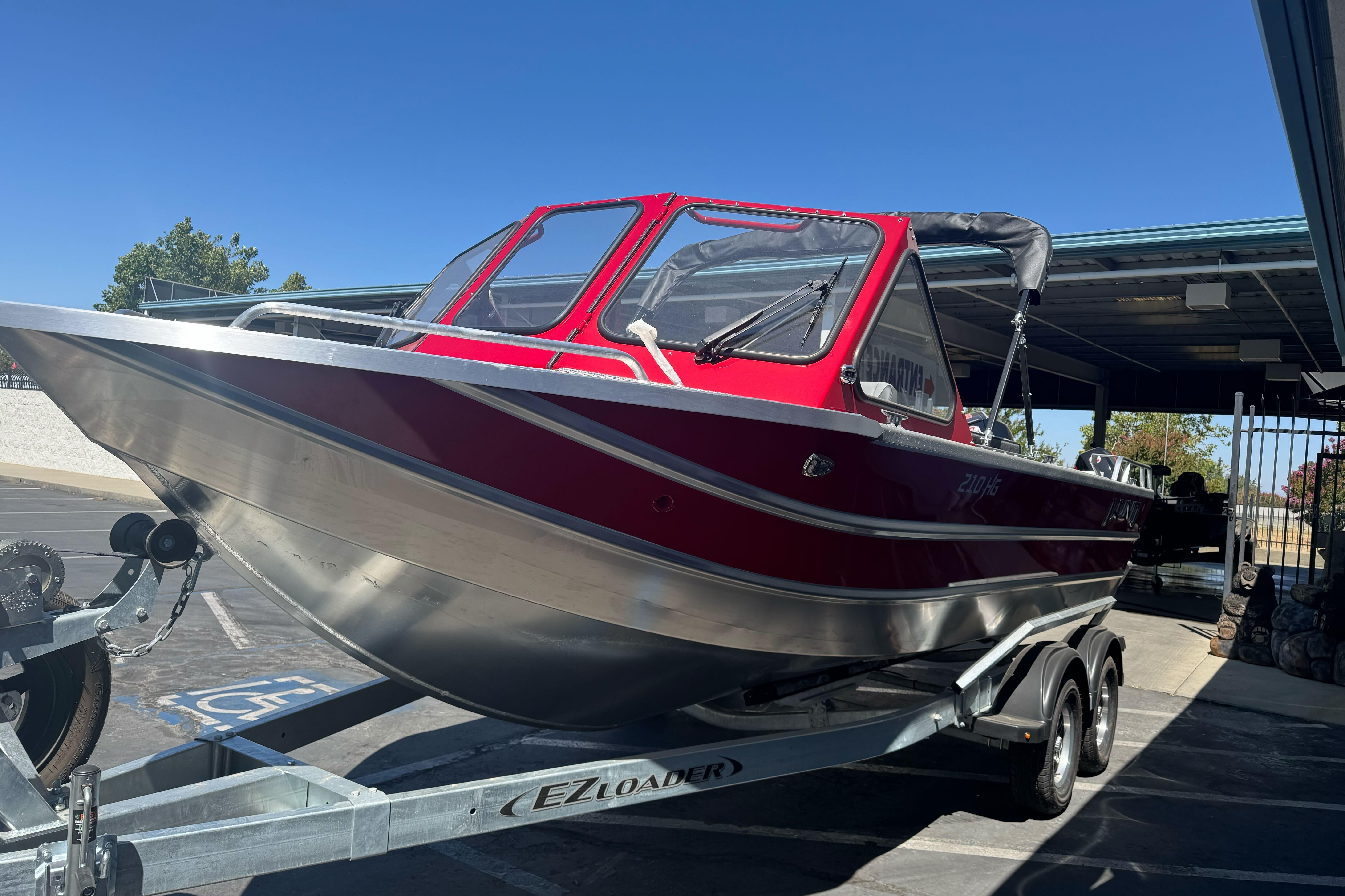 2026 Lund 210 Heavy Gauge boat on trailer, parked outdoors under clear blue sky.
