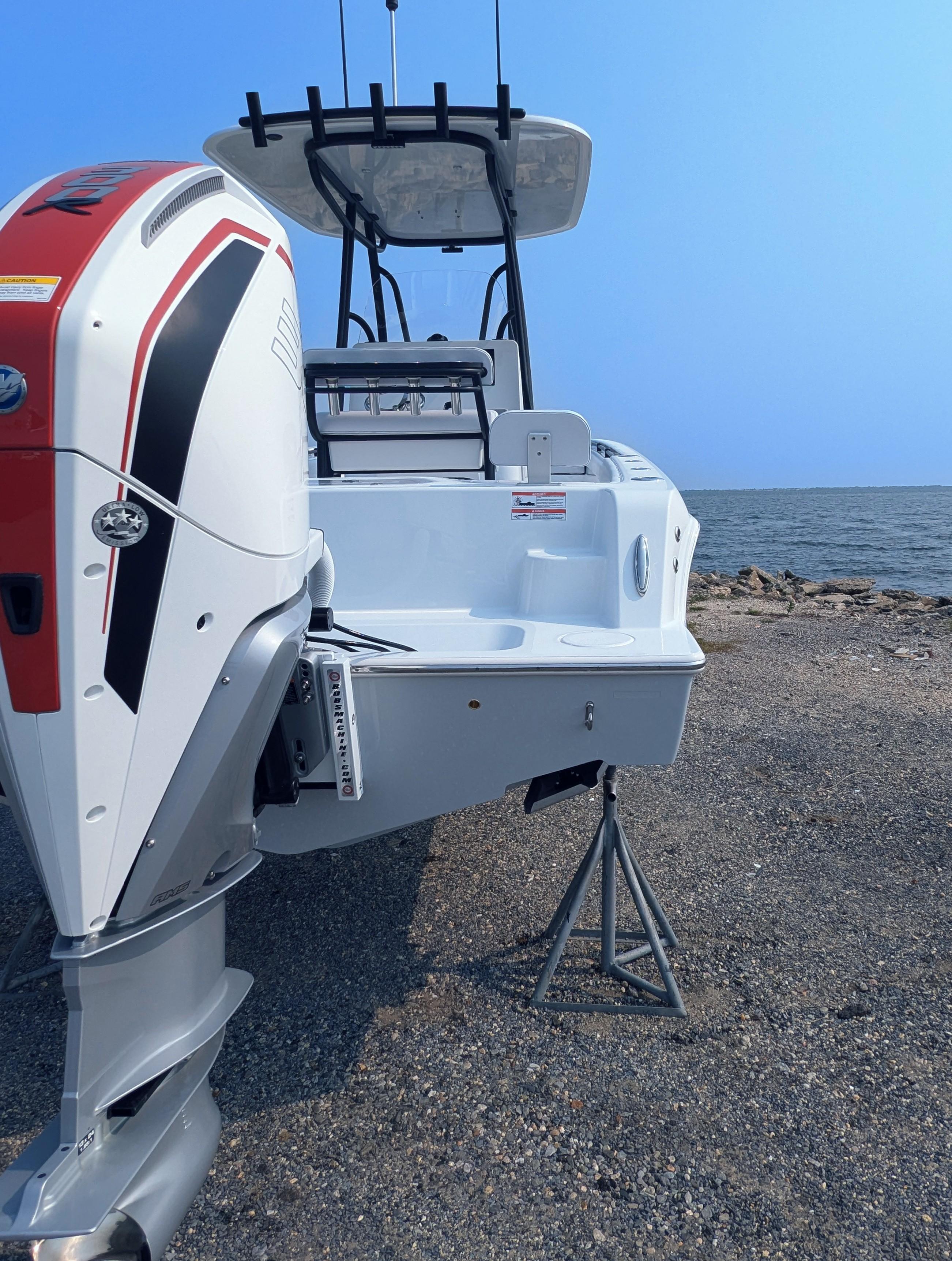 2025 Contender 24 Sport boat with powerful outboard motor by the shore.