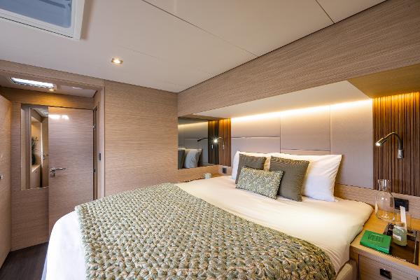 Luxurious bedroom interior of 2025 Lagoon 60 yacht with modern design and cozy bedding.