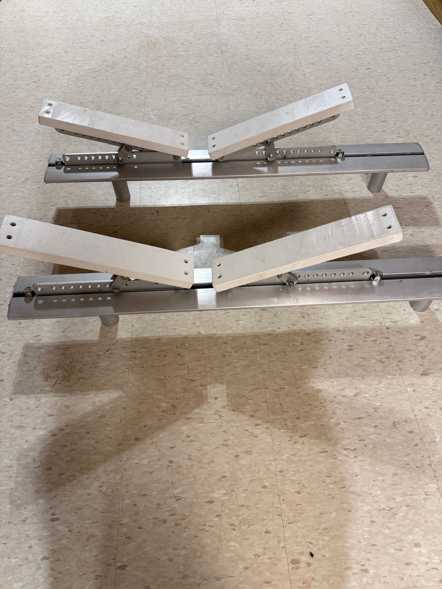 Two metal frames with adjustable arms on a floor.