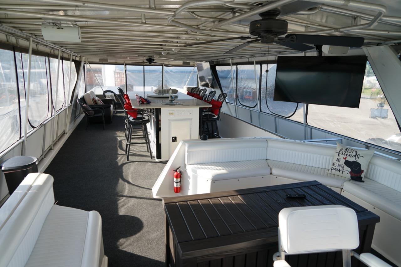 Luxurious interior of a 2000 Stardust Cruisers houseboat with seating, bar, and TV.