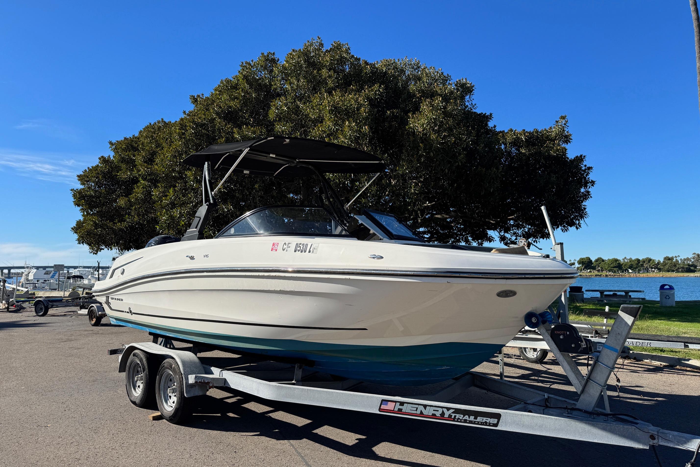 2022 Bayliner VR6 Bowrider OB on trailer, parked near a lake under a clear blue sky.