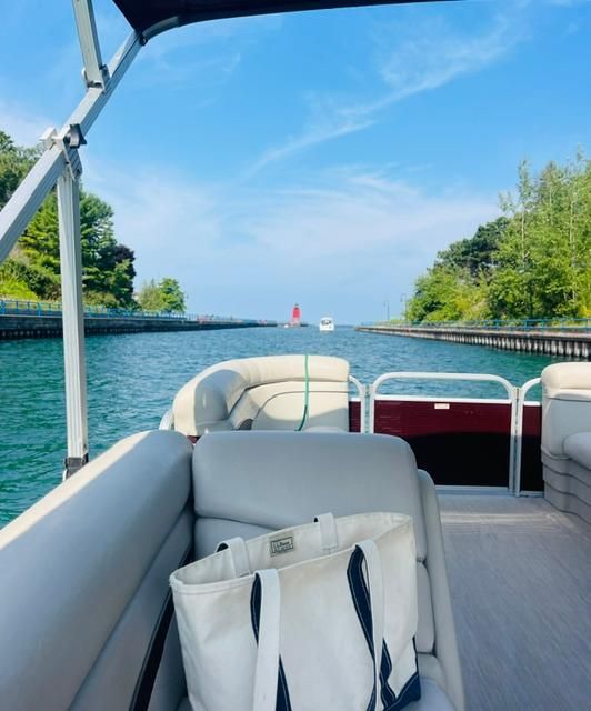 A 2018 Bennington 18SL pontoon boat navigates a canal with clear water and green banks.
