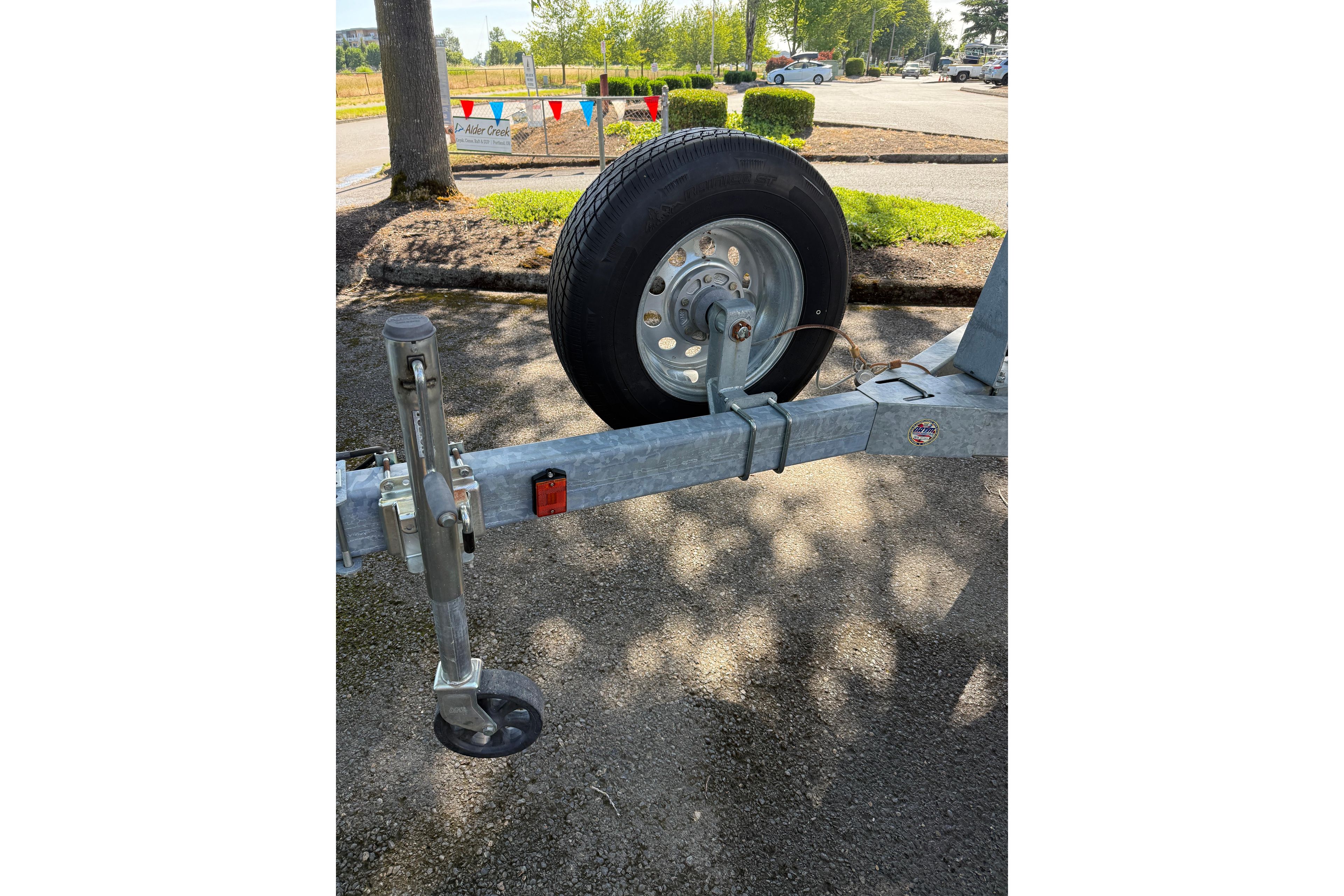 Trailer hitch and wheel for 2004 Sea Ray 240 Sundancer boat in parking lot.