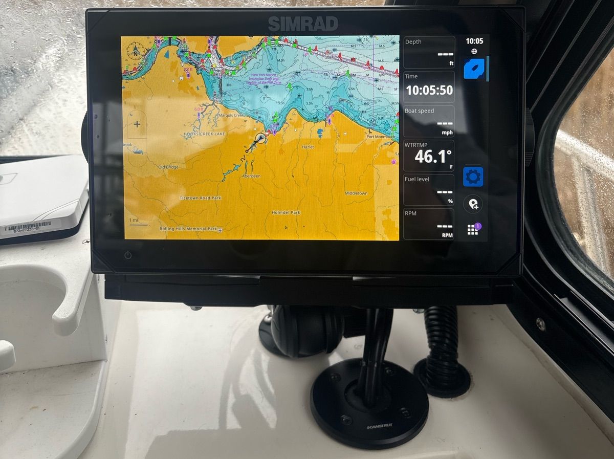 A Simrad navigation system displays a nautical chart and various boat parameters.