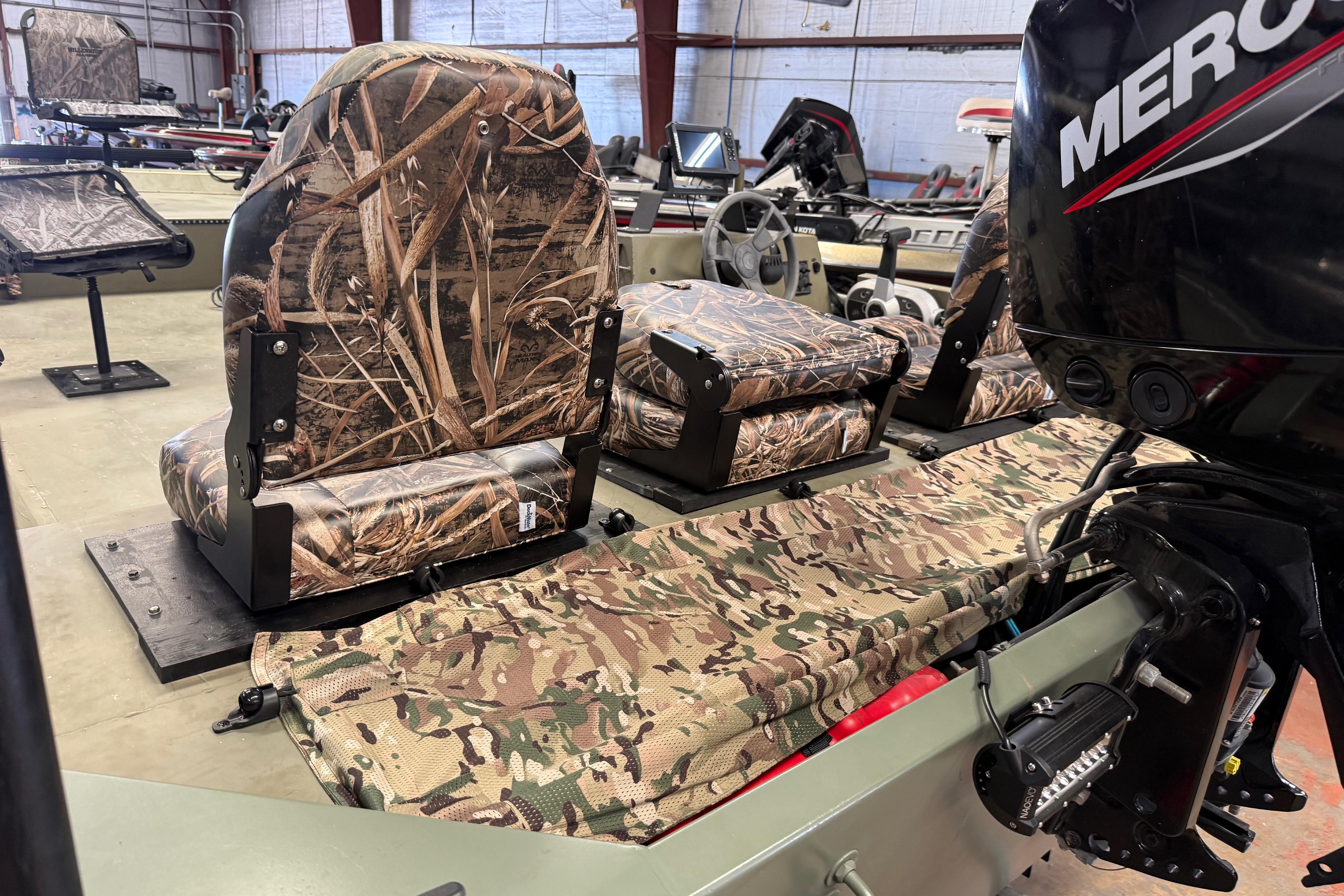 2020 Lowe Roughneck 2070 Big River boat with camo seats and Mercury engine in a workshop.