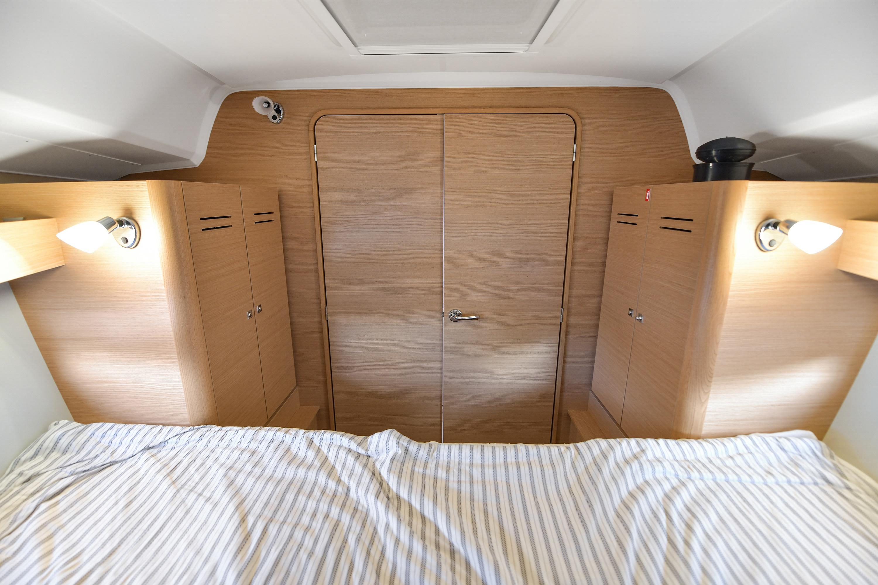 2019 Dufour 382 Grand Large cabin interior with wood finish and striped bedding.