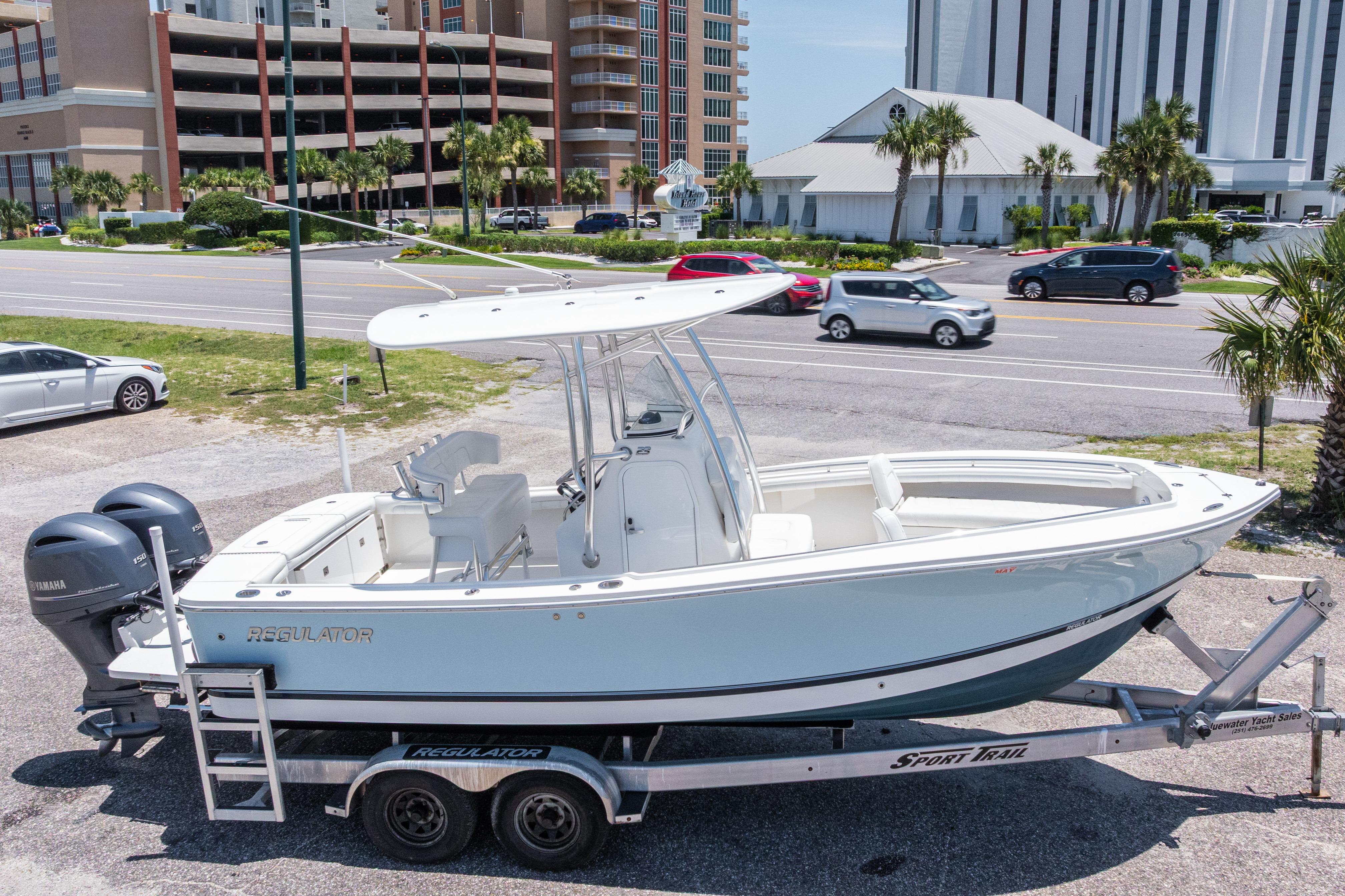 2019 Regulator 23 Center Console boat on trailer, parked near a road with buildings.