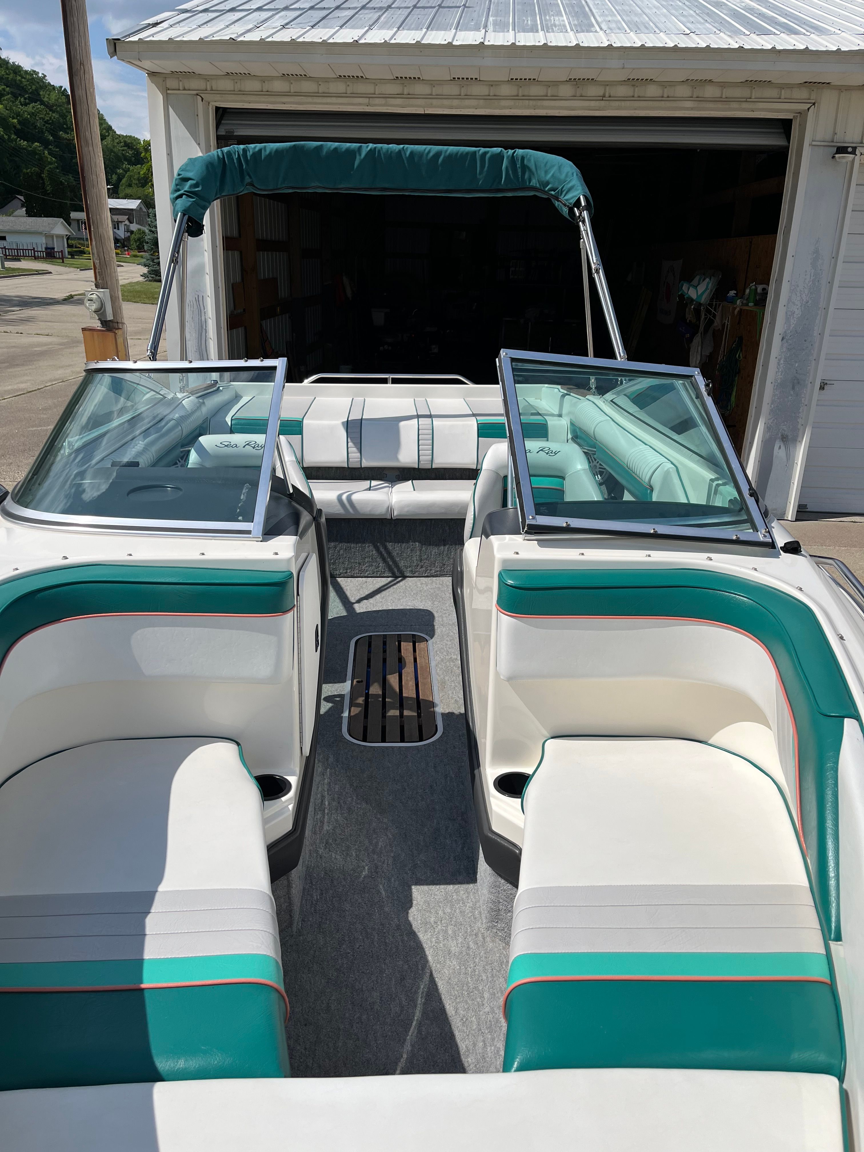 A 1992 Sea Ray 220 Bow Rider with green and white seats and an open canopy.