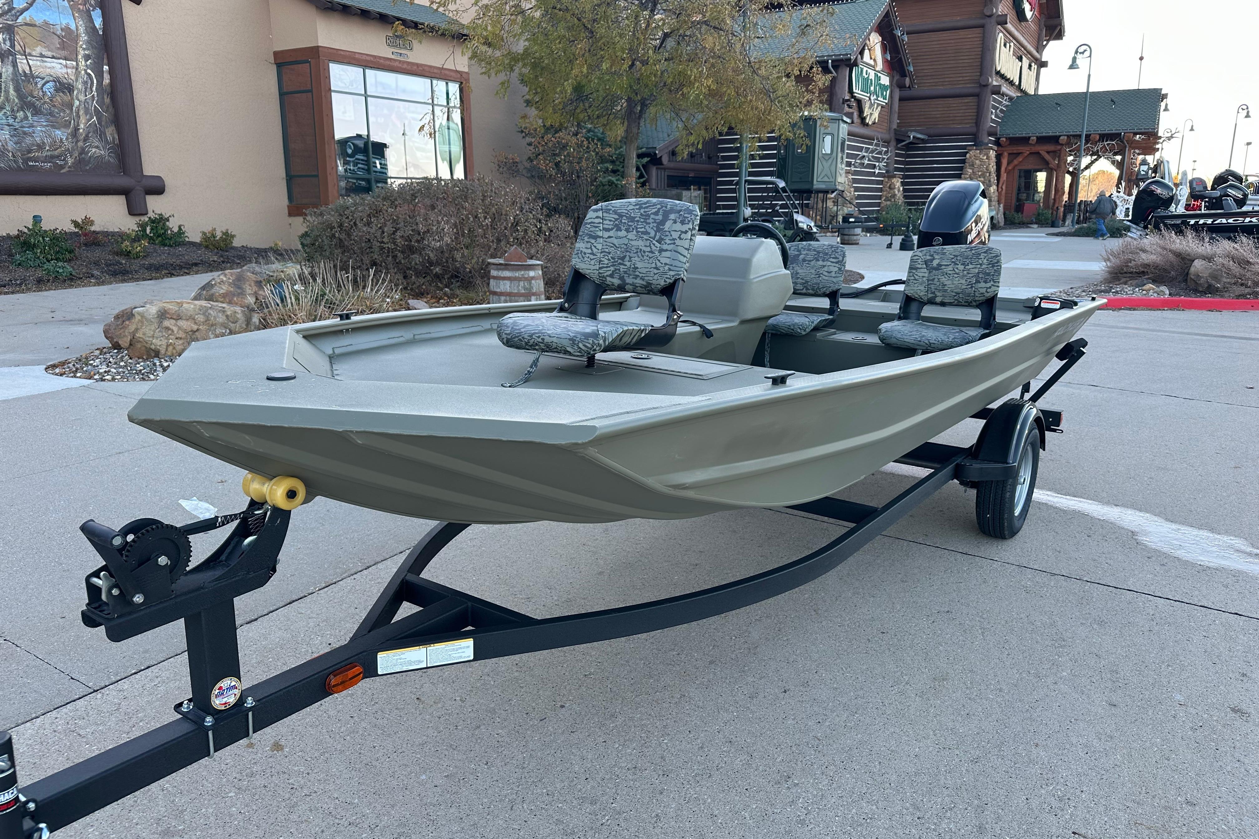 2026 Tracker Grizzly 1754 SC boat on trailer, parked outdoors near rustic buildings.