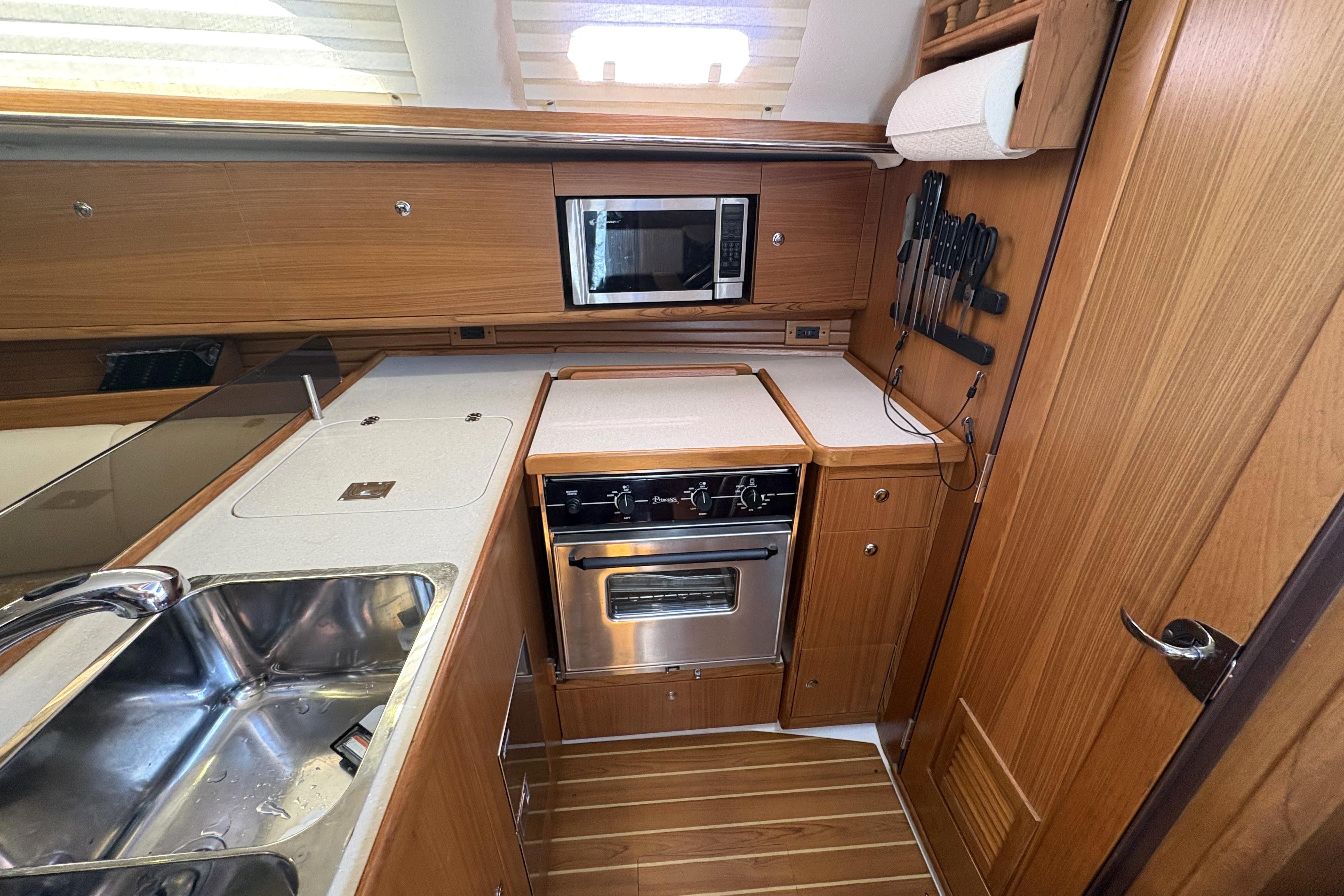 Modern kitchen in a 2011 Catalina 355 yacht with wood cabinetry and stainless steel appliances.
