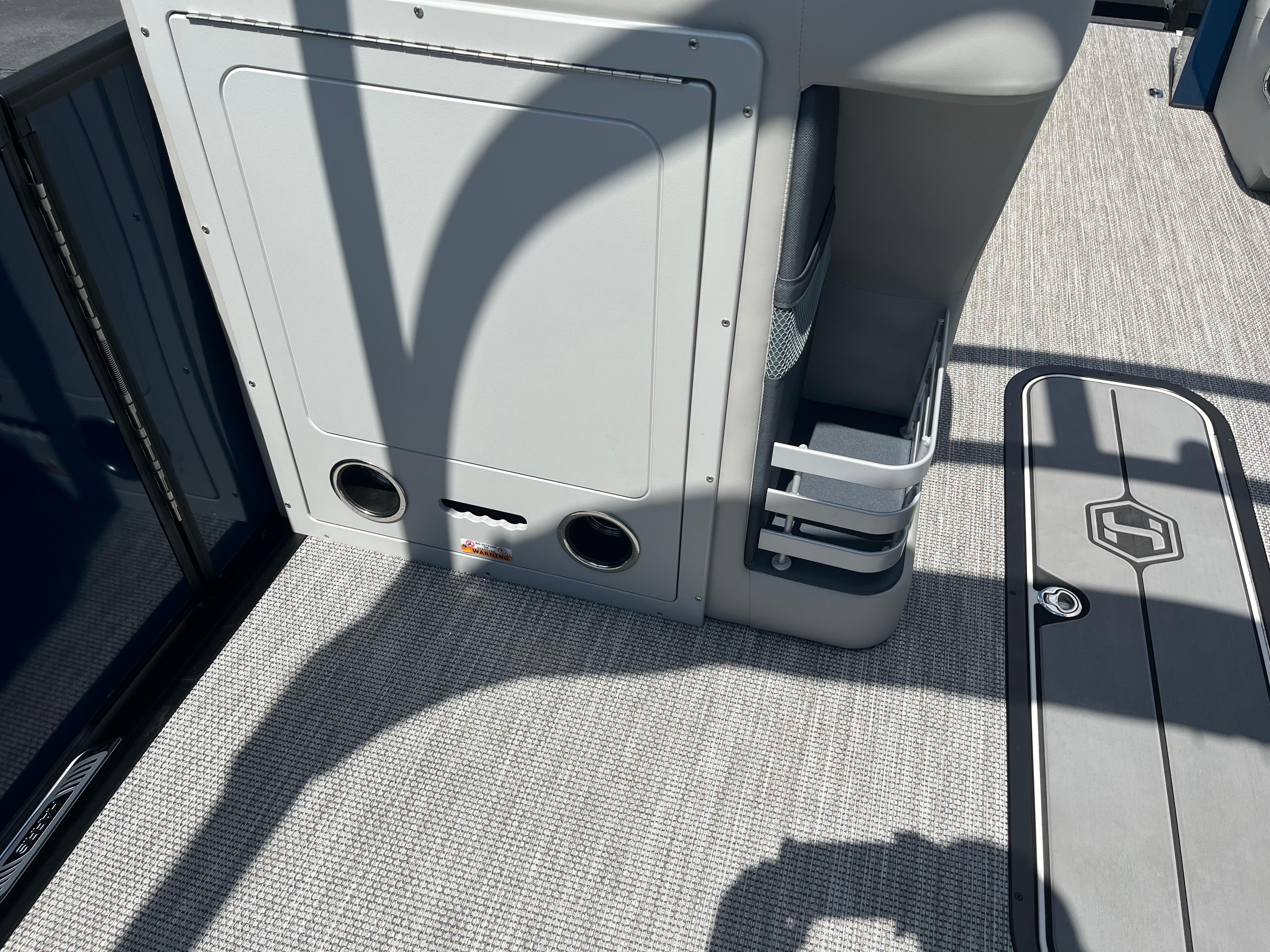 Interior of 2026 Harris Grand Mariner 230 boat, featuring storage compartments and carpeted flooring.
