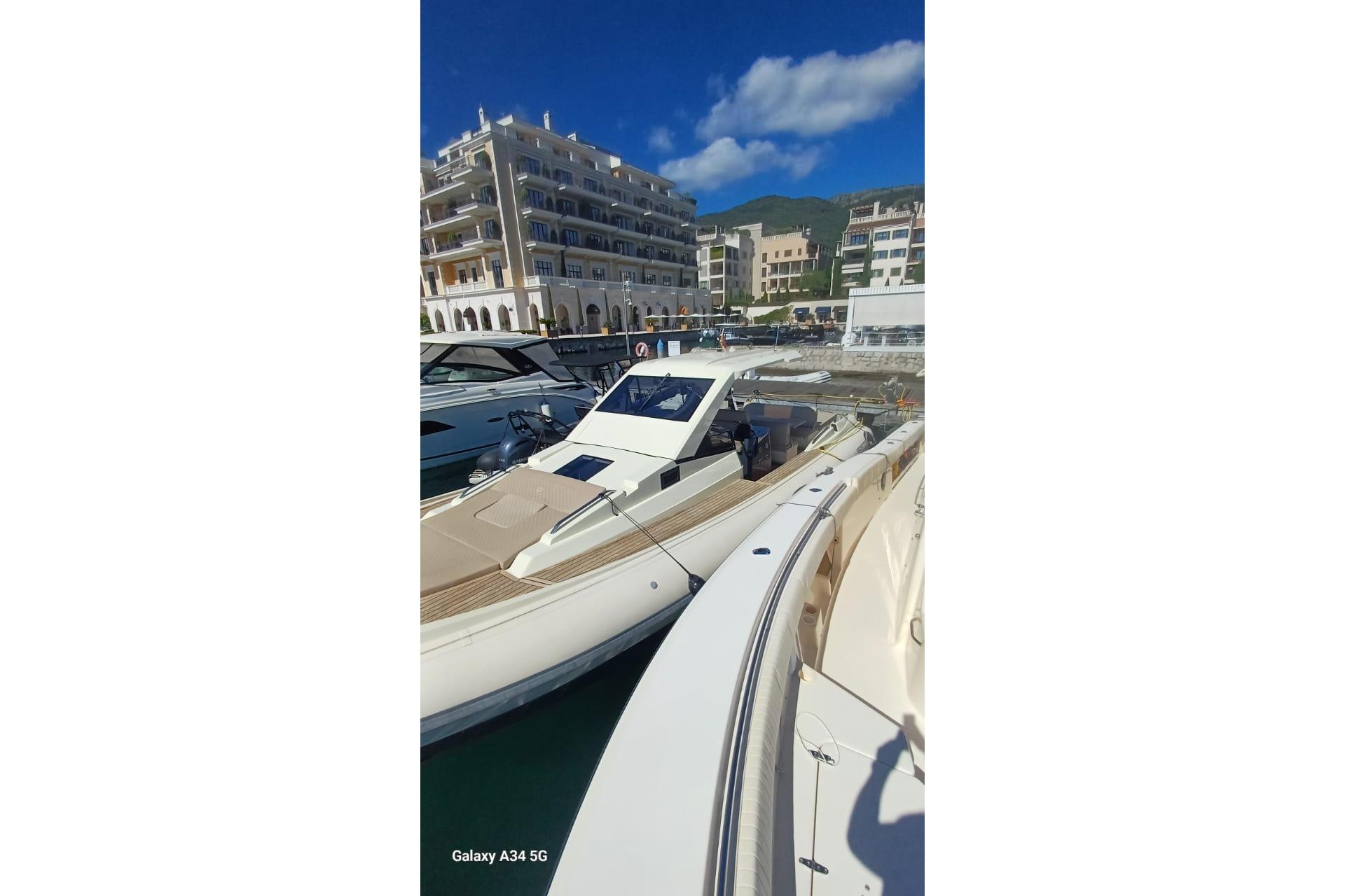 Luxury yachts docked at a marina with scenic buildings in the background.