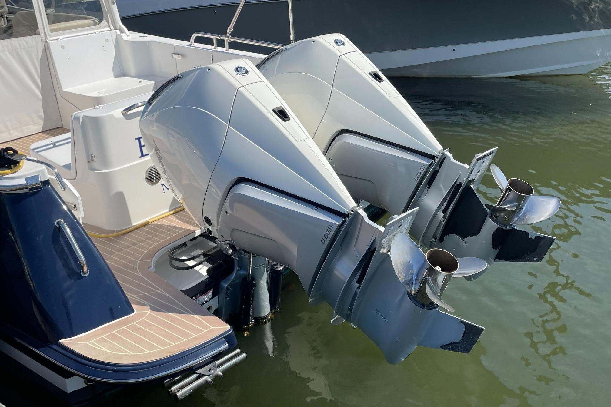 Twin outboard engines on a 2023 MJM 35 boat, docked in water.