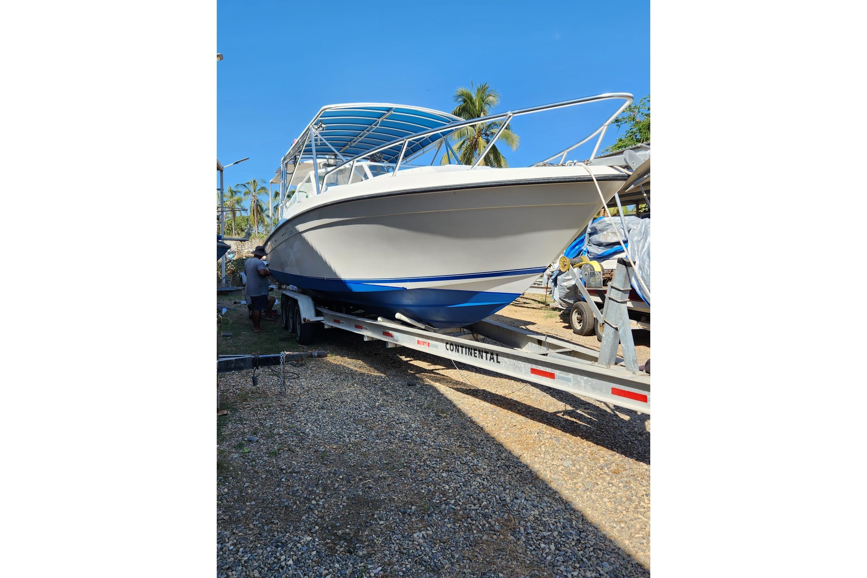 2008 Contender 35 Express Side Console boat on trailer, sunny day, palm trees in background.